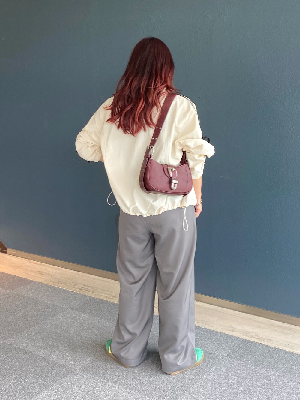 ホワイト系のブルゾン、グレー系のスラックス、レッド系のショルダーバッグを着用したレディースの秋コーディネートの3枚目の写真