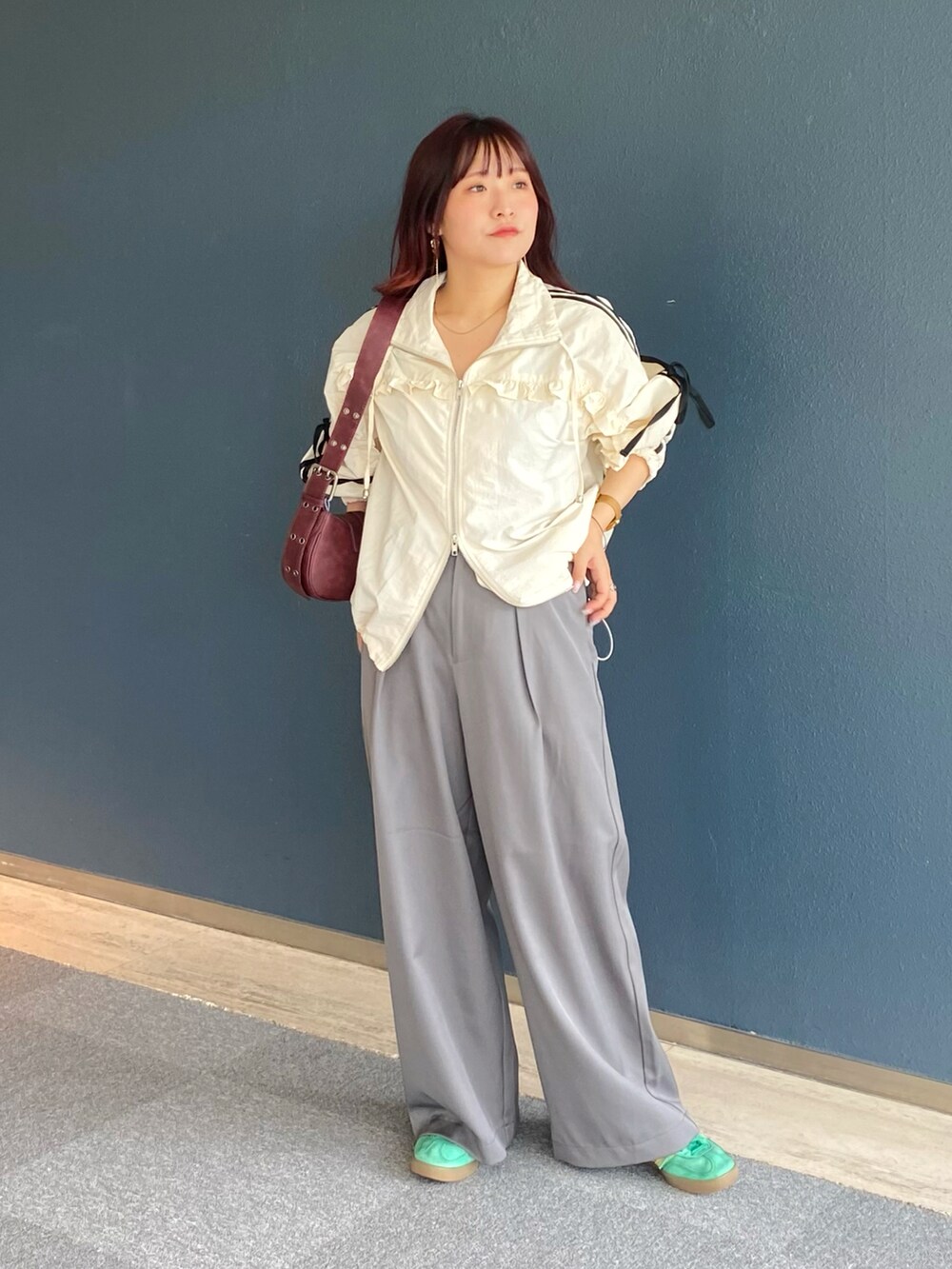 ホワイト系のブルゾン、グレー系のスラックス、レッド系のショルダーバッグを着用したレディースの秋コーディネートの2枚目の写真