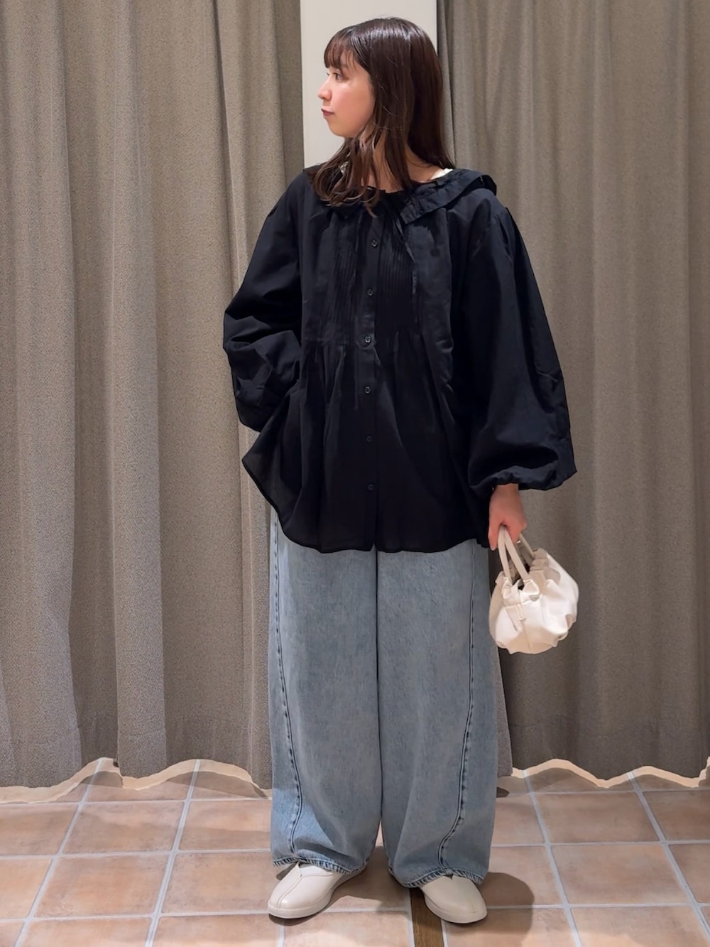 ベージュ系のショルダーバッグ、ホワイト系のスニーカー、ブラック系のシャツ/ブラウスを着用したレディースの冬コーディネートの2枚目の写真