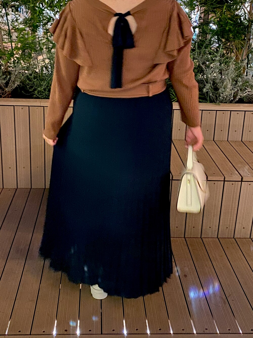 ホワイト系のハンドバッグ、ベージュ系のスカート、ベージュ系のパンプスを着用したレディースの秋コーディネートの2枚目の写真