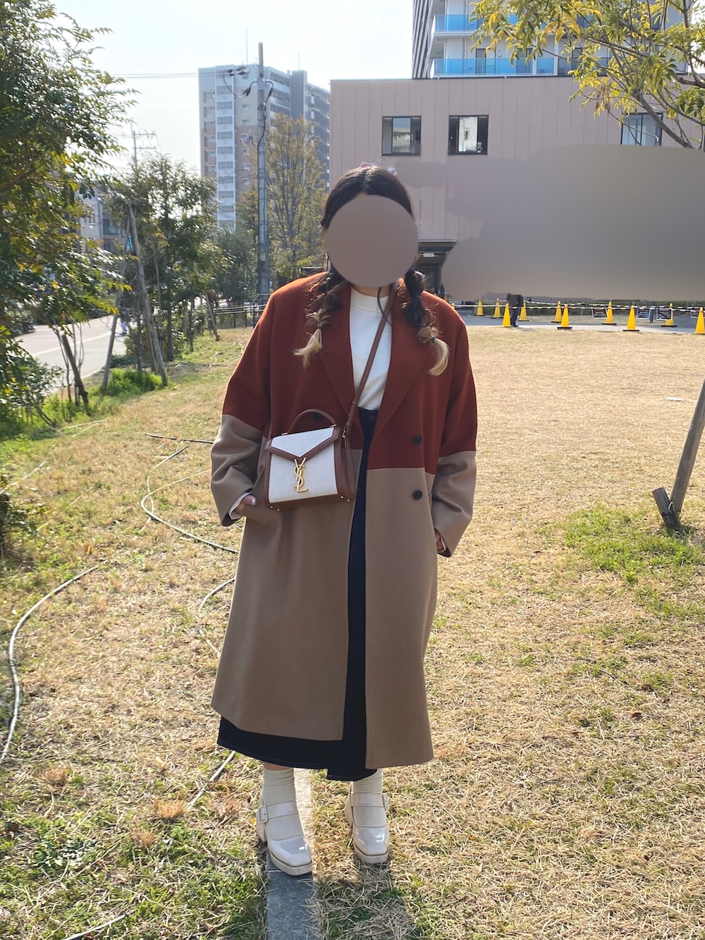 ベージュ系のチェスターコート、ベージュ系のパンプス、ブルー系のデニムスカートを着用したレディースの春コーディネートの2枚目の写真