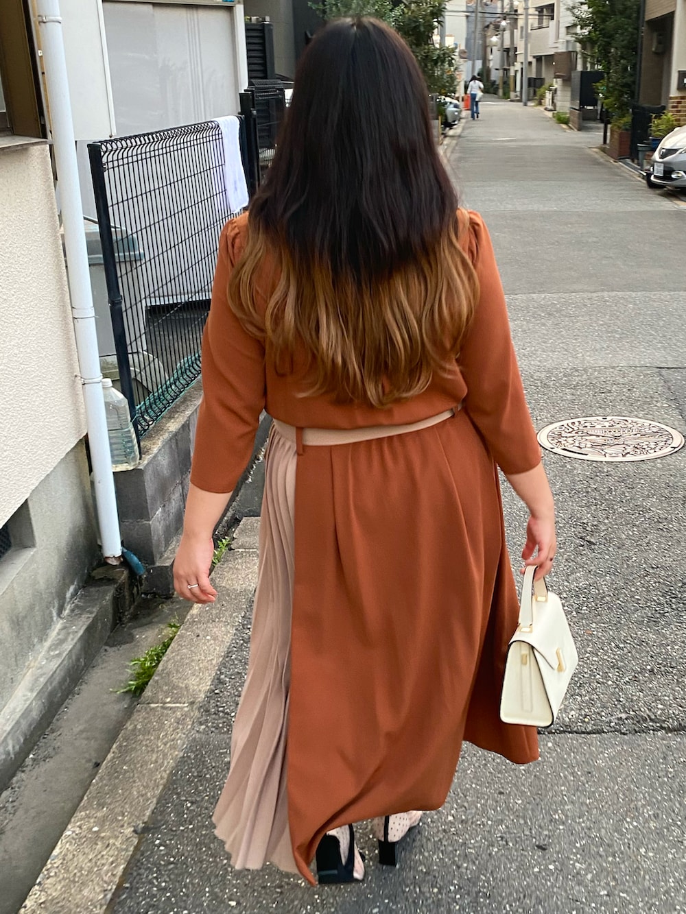 オレンジ系のワンピース、ホワイト系のハンドバッグ、ベージュ系のブーツを着用したレディースの秋コーディネートの2枚目の写真