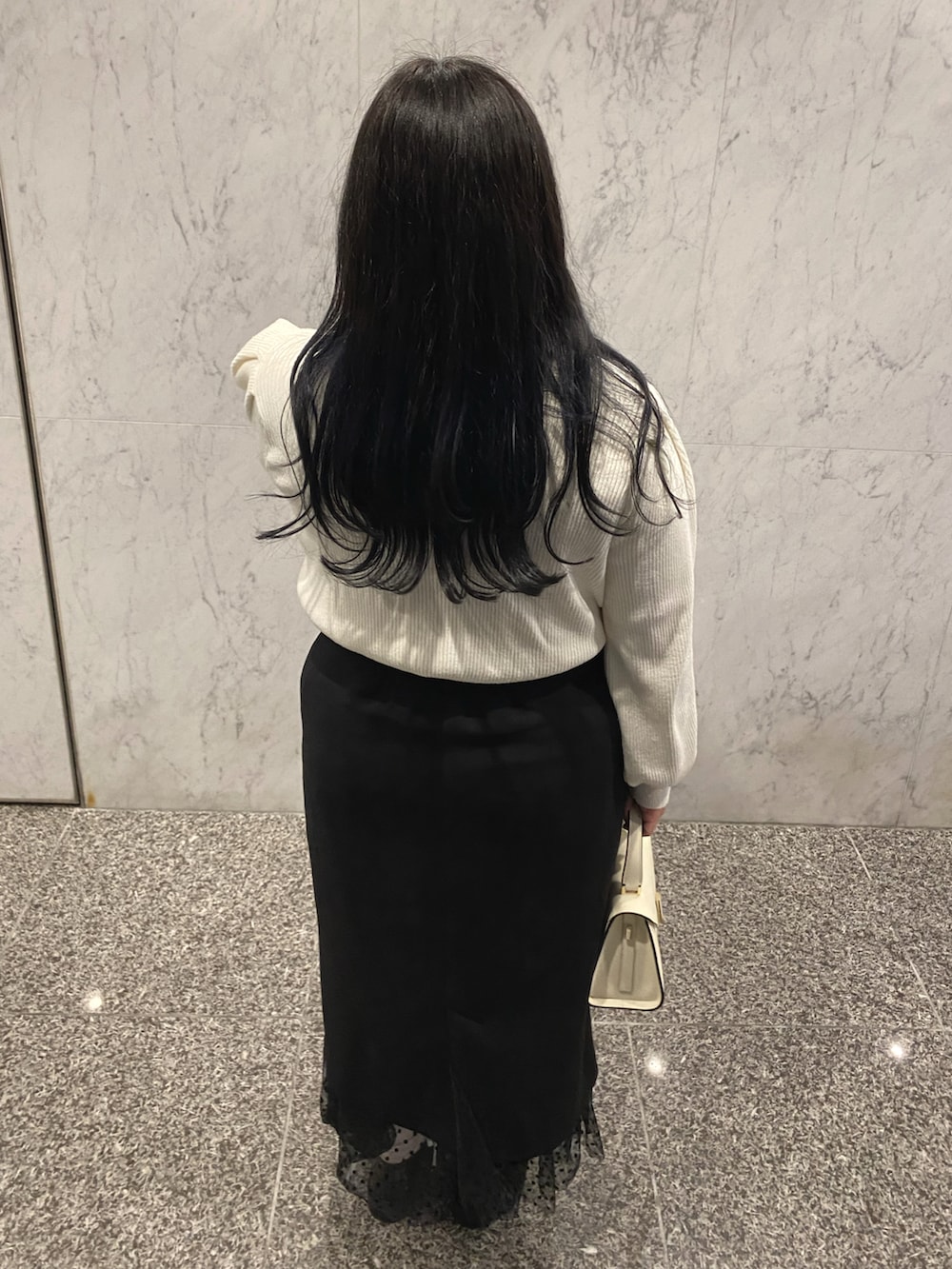 ホワイト系のハンドバッグ、ブラック系のローファー、ブラック系のスカートを着用したレディースの冬コーディネートの3枚目の写真