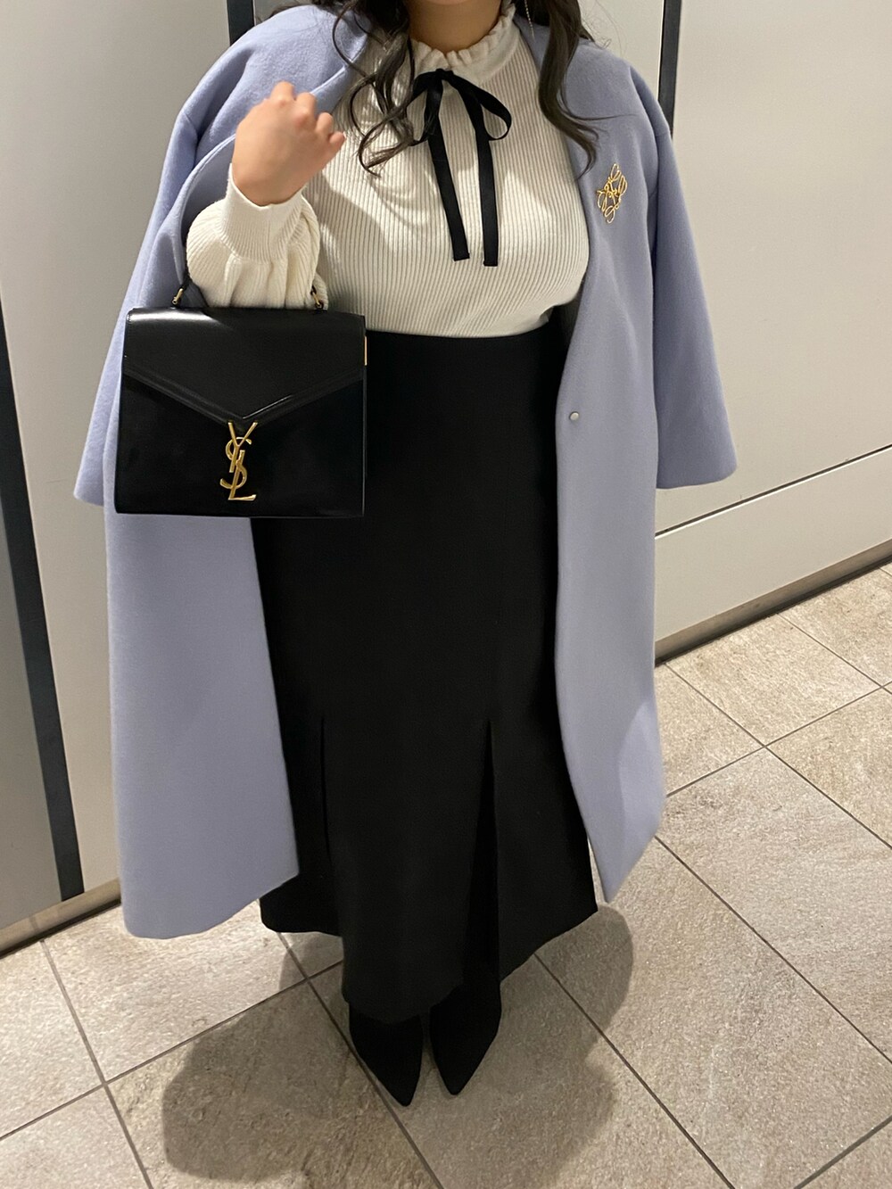 ブラック系のショルダーバッグ、ブルー系のノーカラーコート、ホワイト系のニット/セーターを着用したレディースの冬コーディネートの2枚目の写真