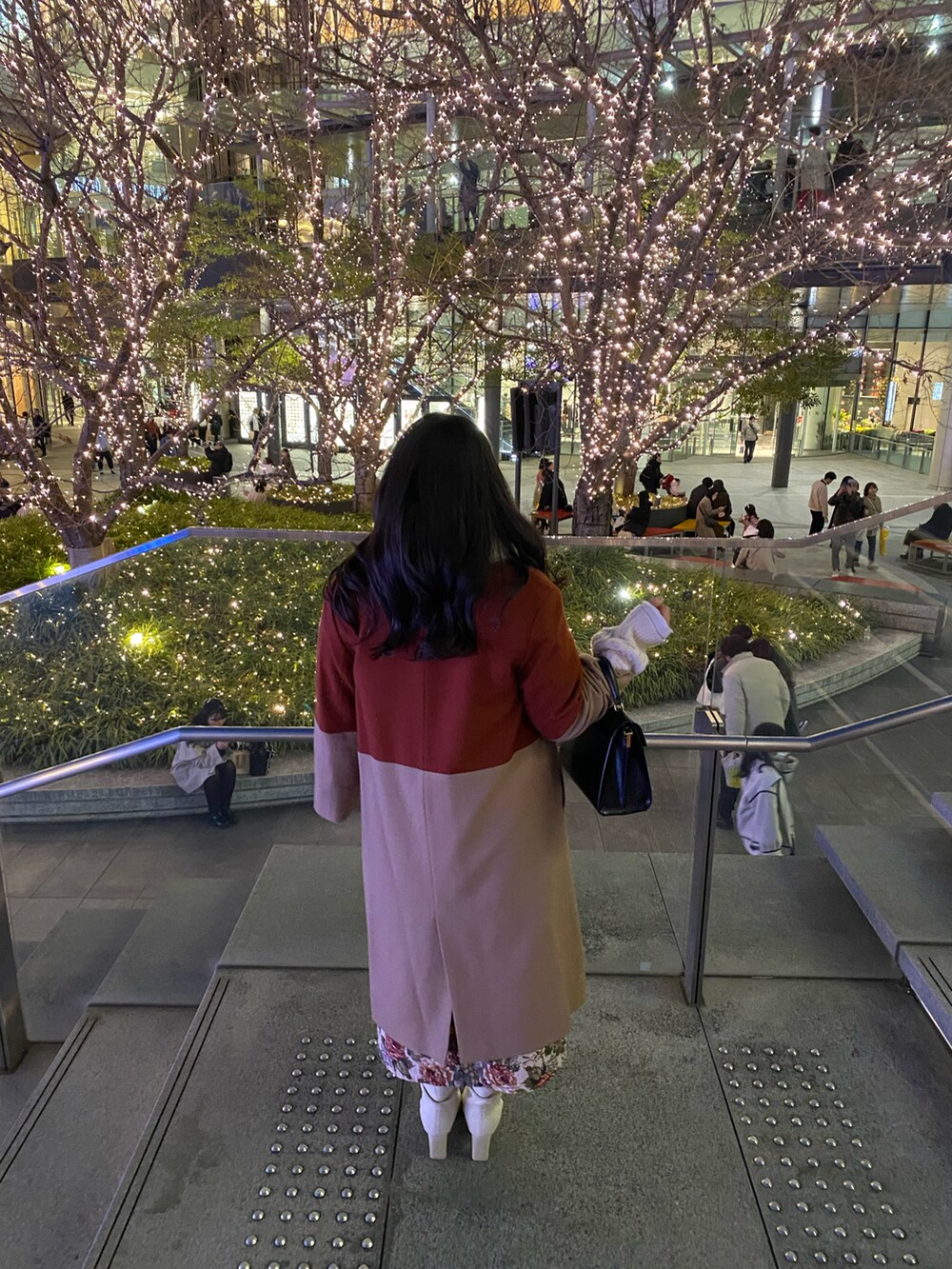 ブラック系のショルダーバッグ、ベージュ系のチェスターコート、ホワイト系のニット/セーターを着用したレディースの冬コーディネートの2枚目の写真