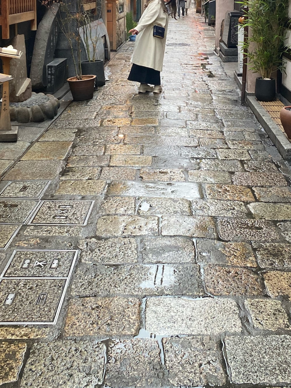 ホワイト系のノーカラーコート、レッド系のニット/セーター、ブルー系のショルダーバッグを着用したレディースの春コーディネートの3枚目の写真