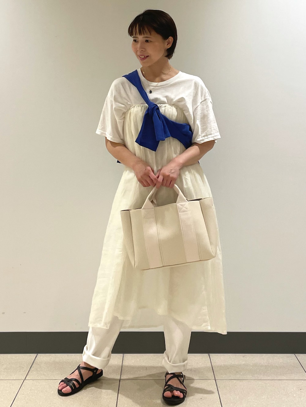 ホワイト系のTシャツ/カットソー、ホワイト系のトートバッグ、ブラック系のサンダルを着用したレディースの夏コーディネートの2枚目の写真