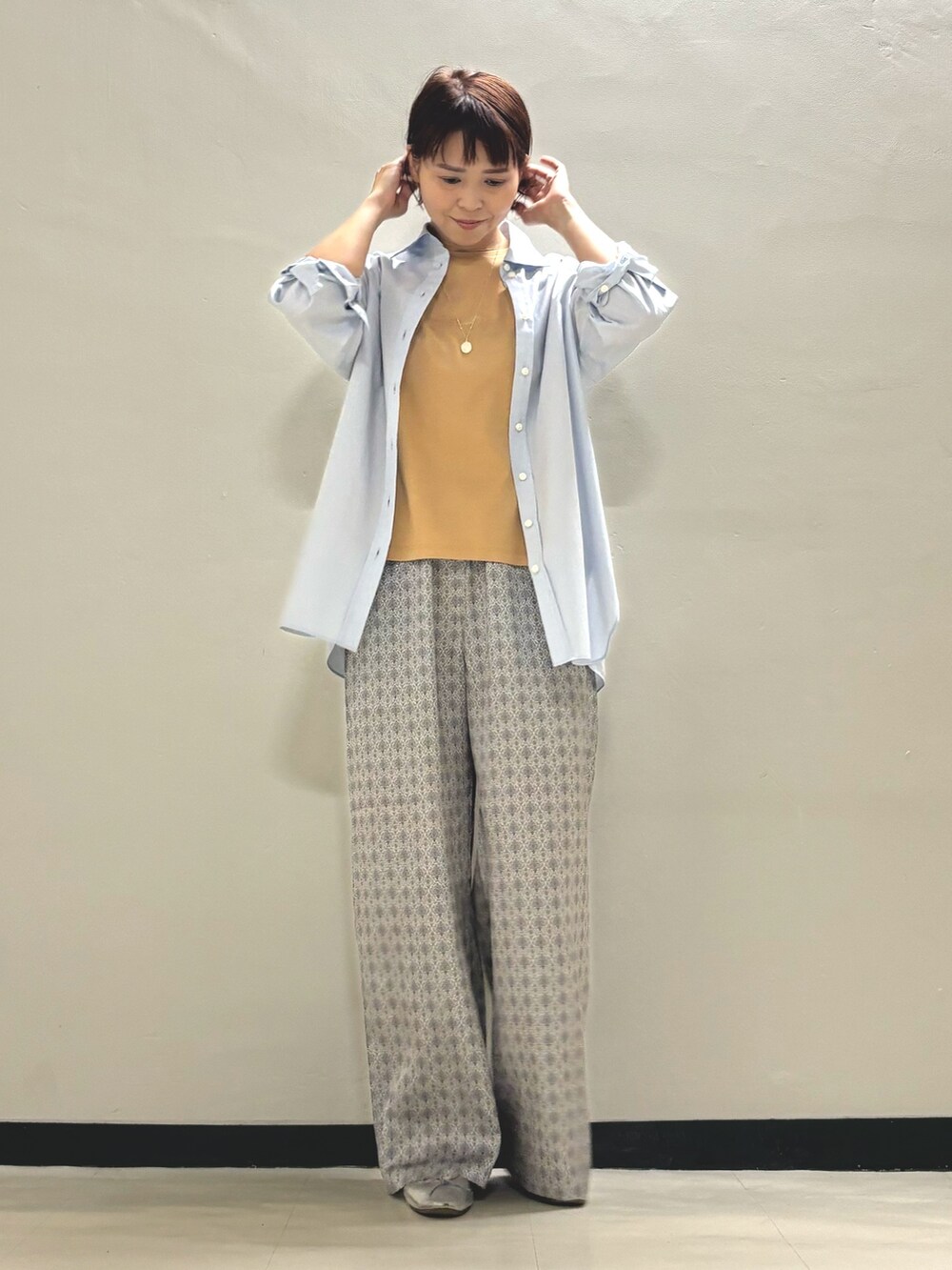 オレンジ系のTシャツ/カットソー、ブルー系のシャツ/ブラウス、ベージュ系のその他パンツを着用したレディースの夏コーディネートの2枚目の写真