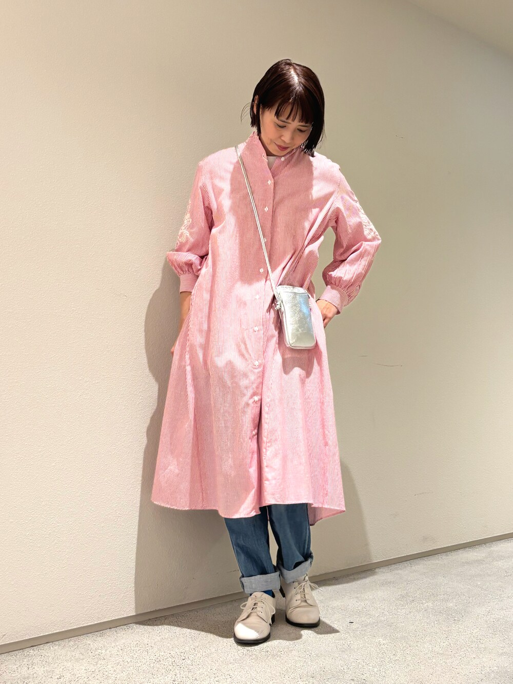 レッド系のワンピース、シルバー系のバッグ、ブルー系のデニムパンツを着用したレディースの春コーディネートの2枚目の写真