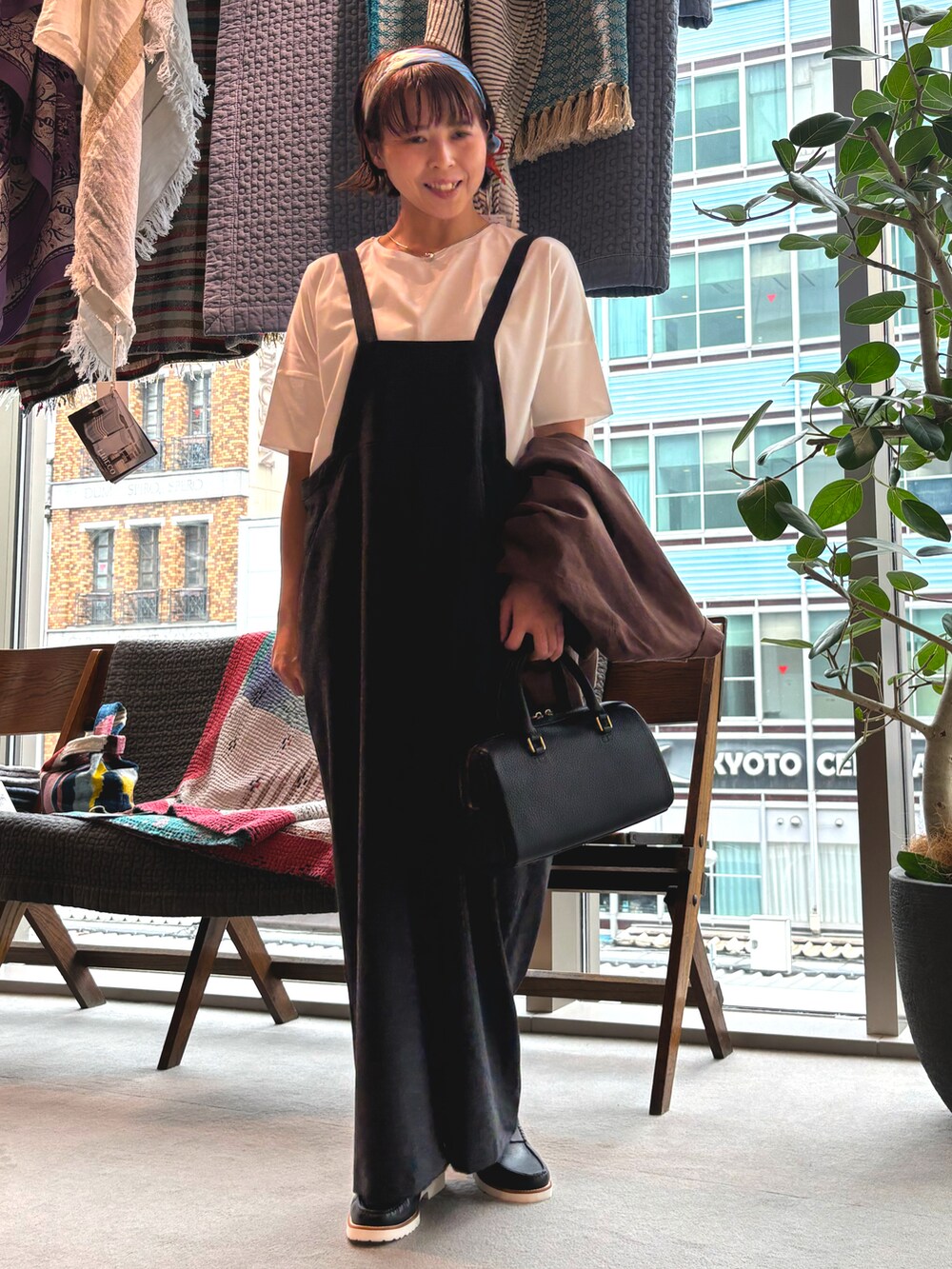 ブラウン系のテーラードジャケット、ブラック系のボストンバッグ、ブラック系のサロペット/オーバーオールを着用したレディースの春コーディネートの3枚目の写真