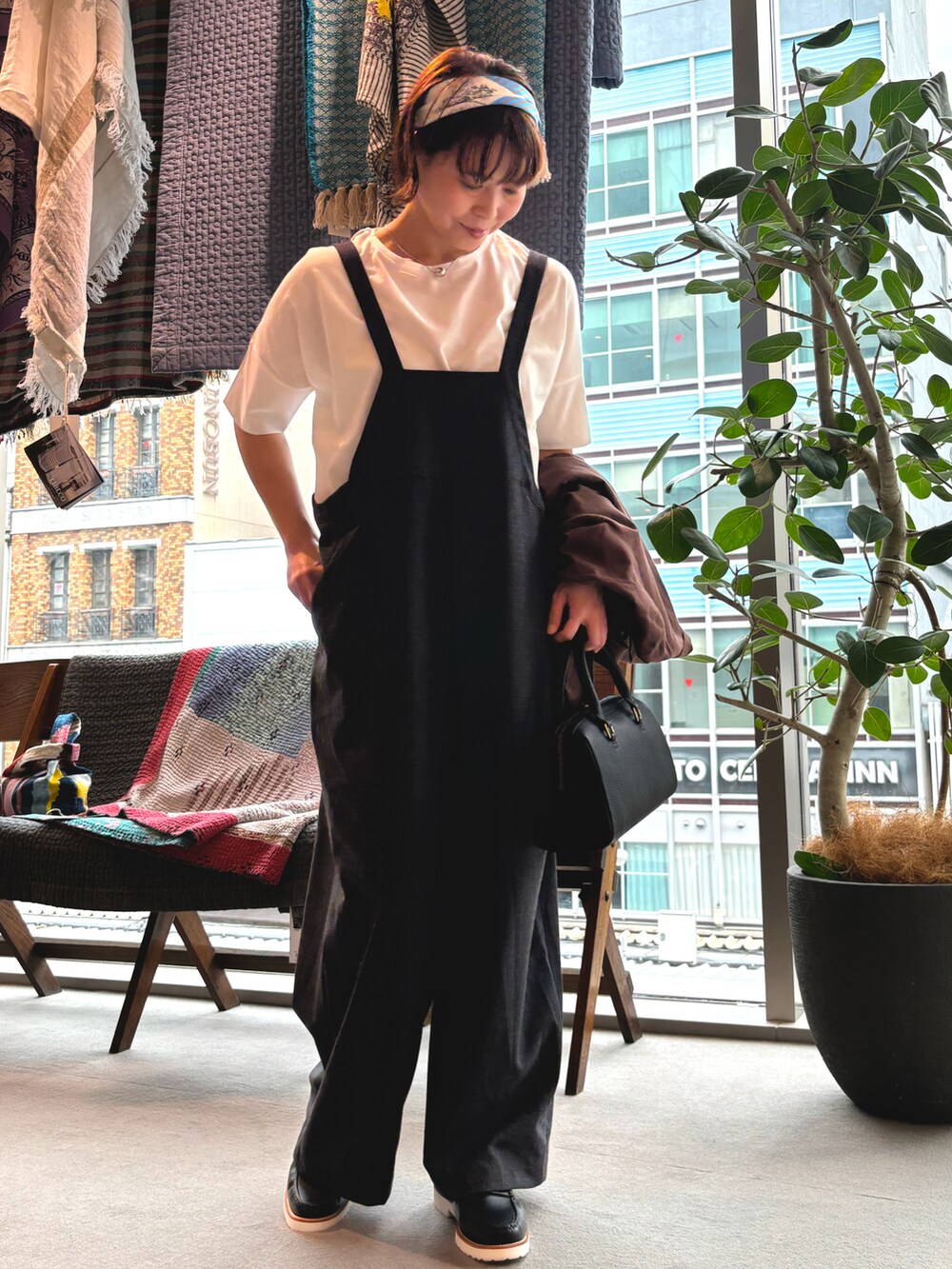 ブラウン系のテーラードジャケット、ブラック系のボストンバッグ、ブラック系のサロペット/オーバーオールを着用したレディースの春コーディネートの2枚目の写真