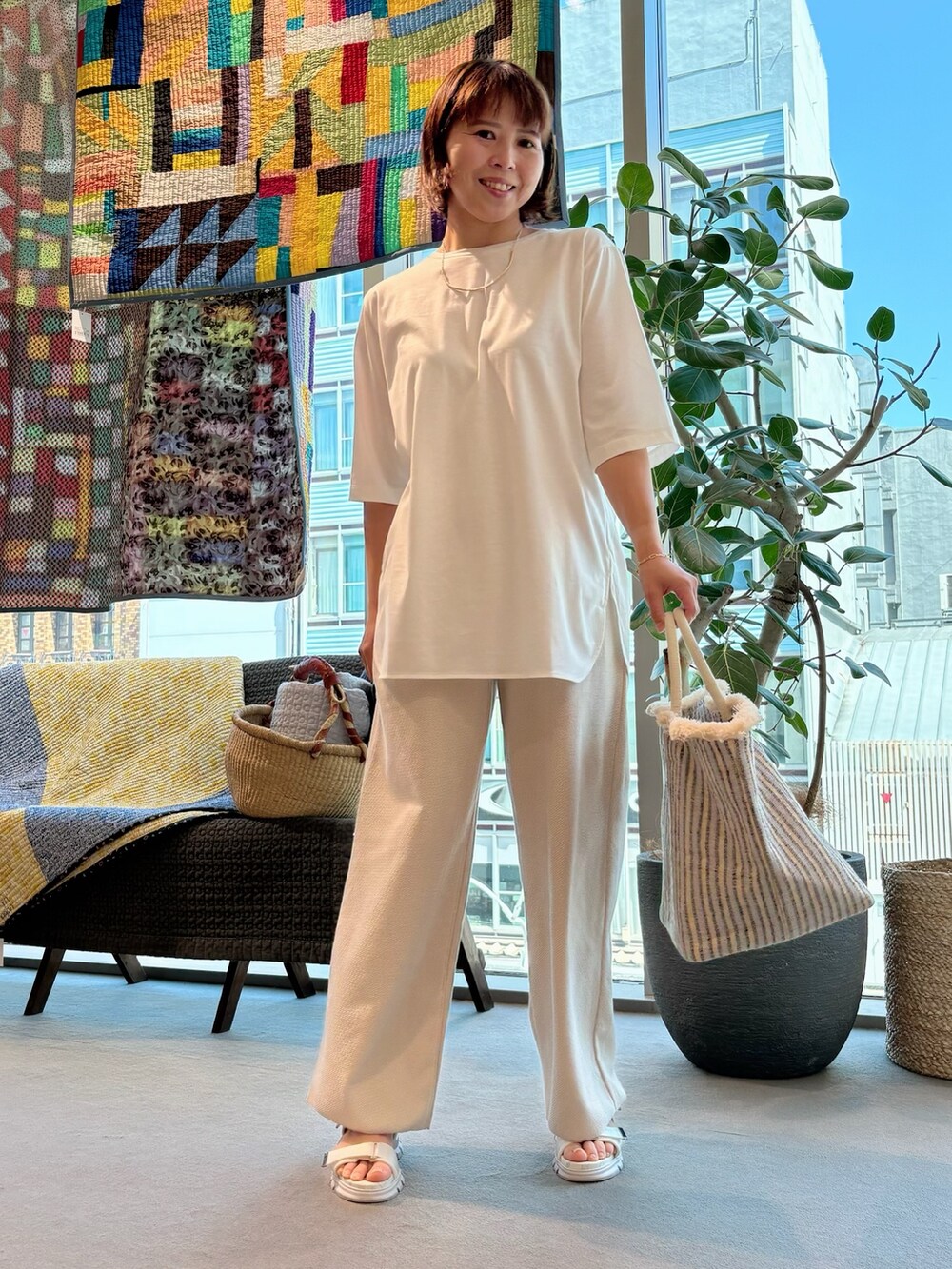 ホワイト系のTシャツ/カットソー、ホワイト系のかごバッグ、ゴールド系のネックレスを着用したレディースの夏コーディネートの2枚目の写真