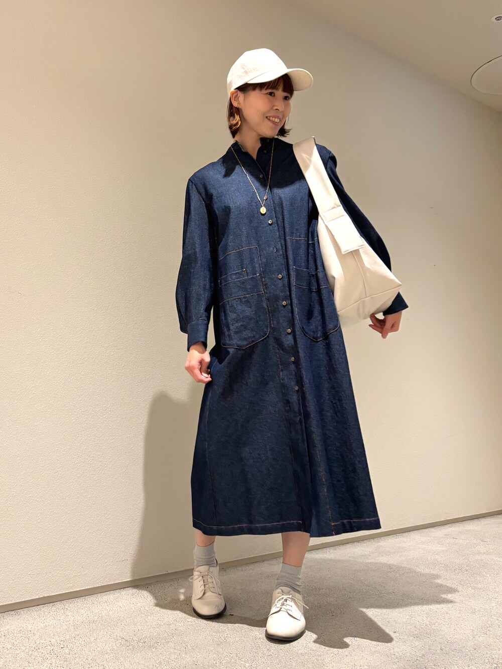 ブルー系のシャツワンピース、ゴールド系のネックレスを着用したレディースの春コーディネートの3枚目の写真