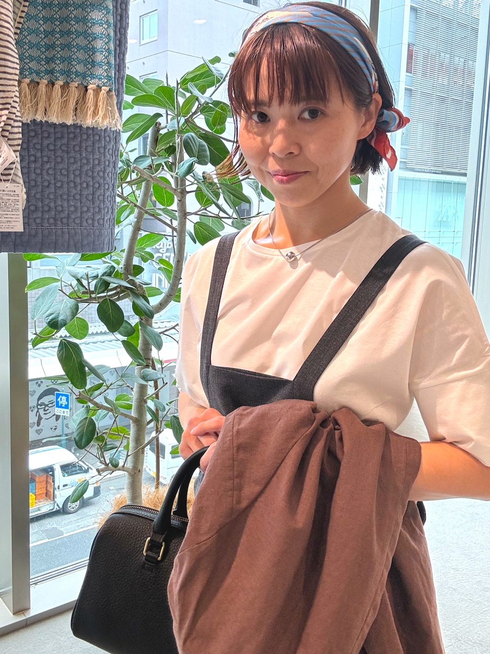 ブラウン系のテーラードジャケット、ブラック系のボストンバッグ、ブラック系のサロペット/オーバーオールを着用したレディースの春コーディネートの4枚目の写真