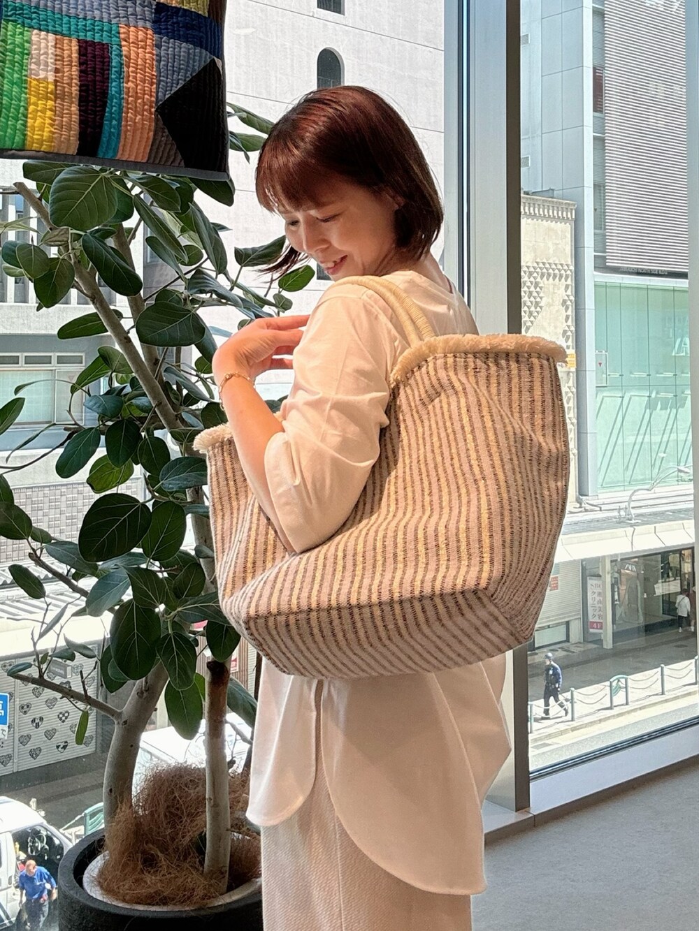 ホワイト系のTシャツ/カットソー、ホワイト系のかごバッグ、ゴールド系のネックレスを着用したレディースの夏コーディネートの5枚目の写真