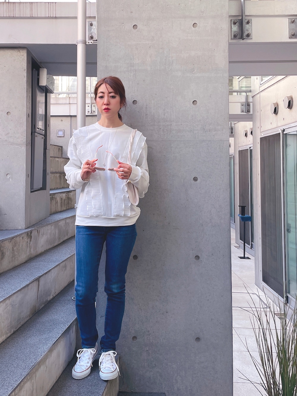 ホワイト系のポロシャツ、ブルー系のデニムパンツ、ホワイト系のスニーカーを着用したレディースの春コーディネートの2枚目の写真