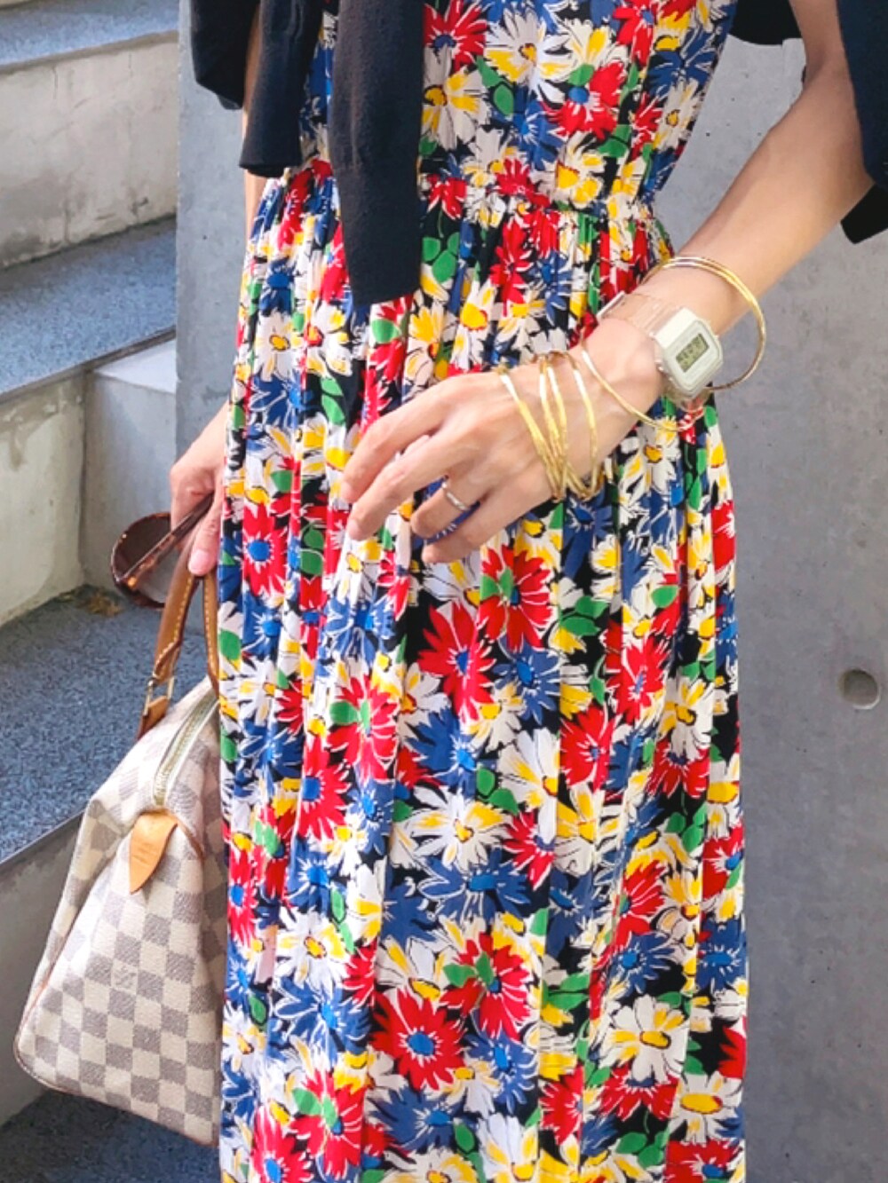 ブラック系のワンピース、ベージュ系のハンドバッグ、ゴールド系のバングル/リストバンドを着用したレディースの夏コーディネートの3枚目の写真