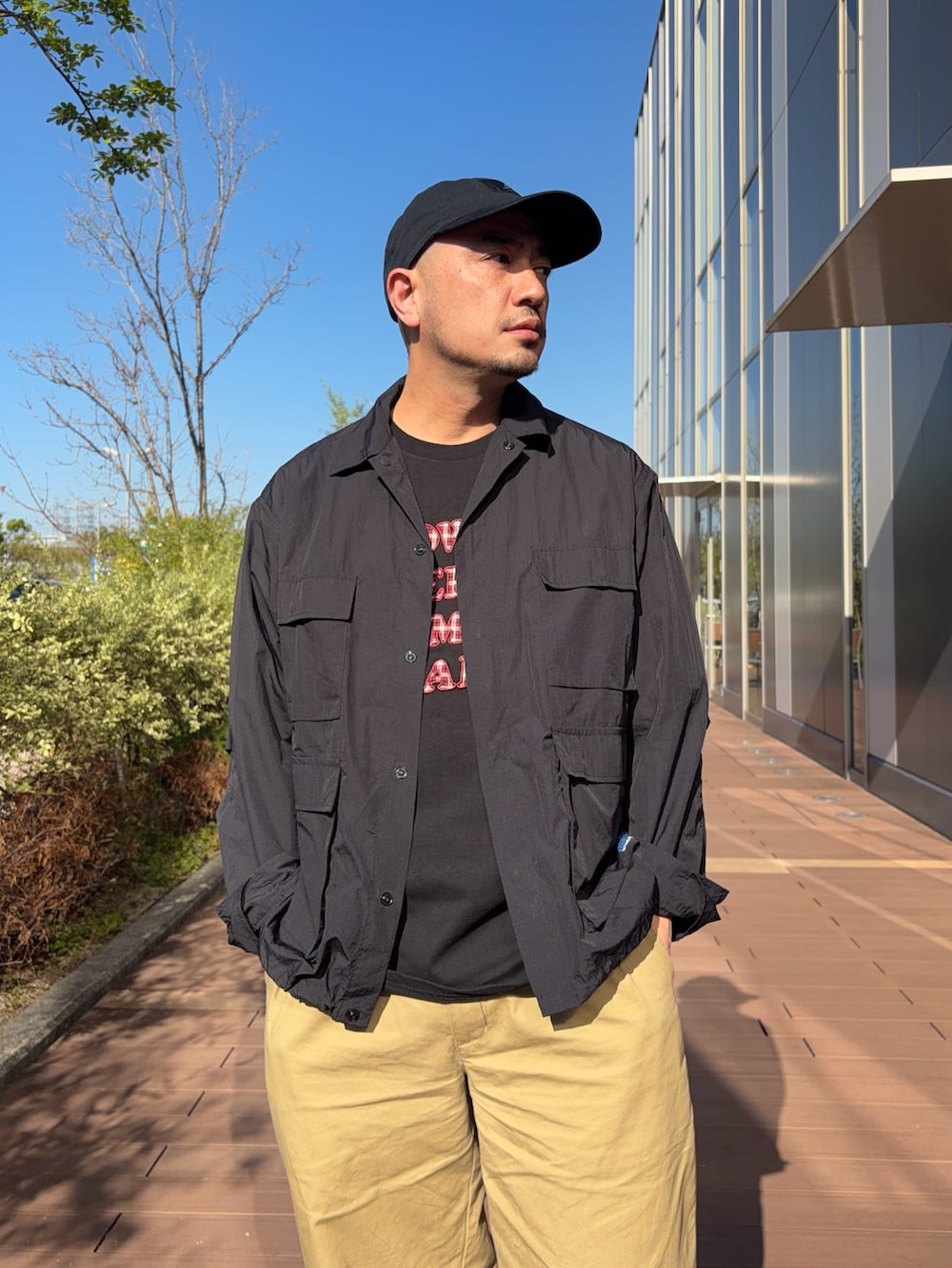 ブラック系のTシャツ/カットソー、ベージュ系のデニムパンツ、ブラック系のナイロンジャケットを着用したメンズの春コーディネートの2枚目の写真
