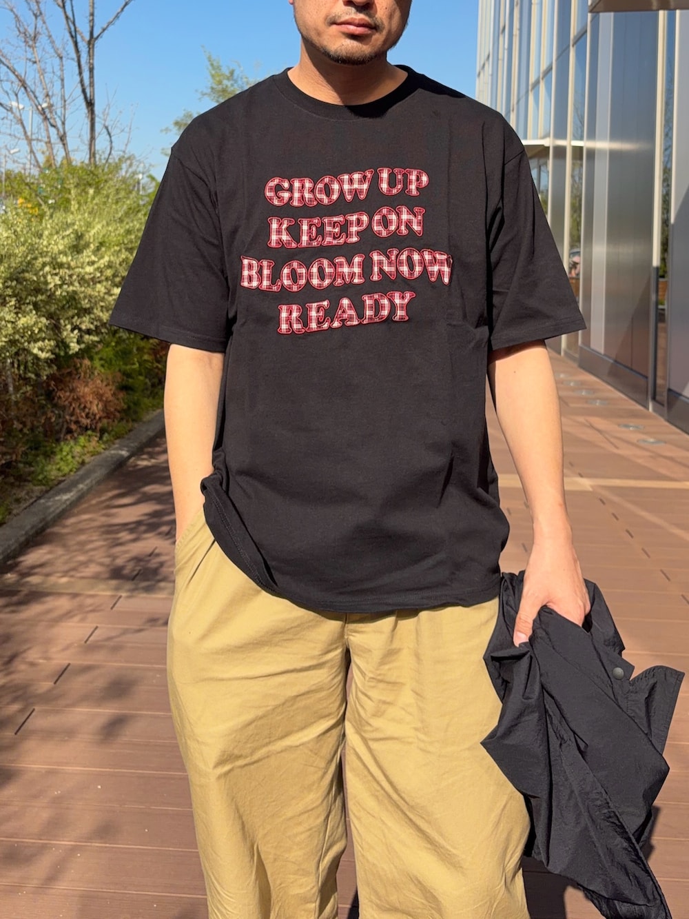 ブラック系のTシャツ/カットソー、ベージュ系のデニムパンツ、ブラック系のナイロンジャケットを着用したメンズの春コーディネートの3枚目の写真