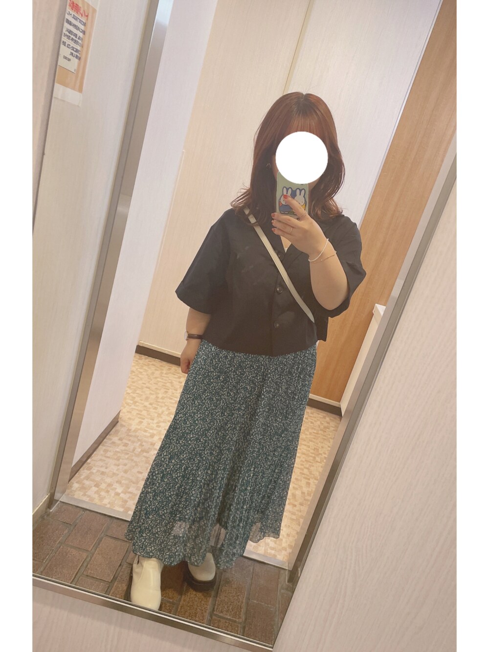 グリーン系のスカート、ブラック系のシャツ/ブラウス、ホワイト系のブーツを着用したレディースの春コーディネートの2枚目の写真