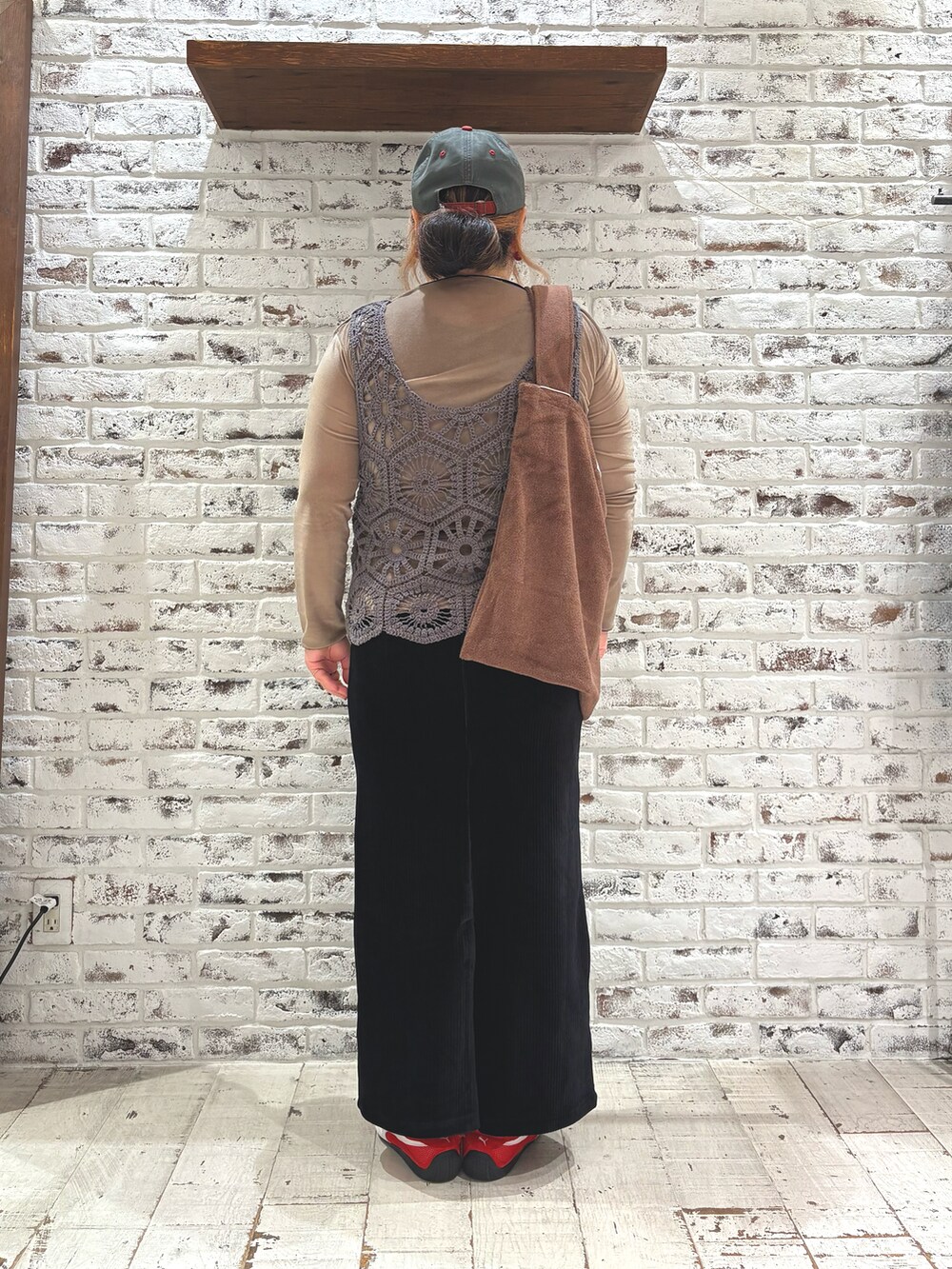 レッド系のスニーカー、グレー系のベスト、ブラック系のスカートを着用したレディースの秋コーディネートの4枚目の写真