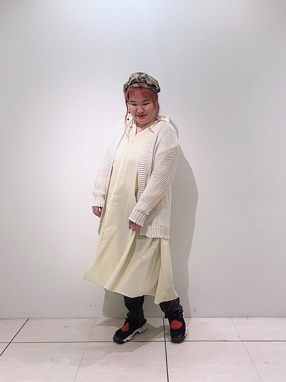 イエロー系のシャツワンピース、ホワイト系のカーディガン/ボレロ、グレー系のデニムパンツを着用したレディースの春コーディネートの2枚目の写真