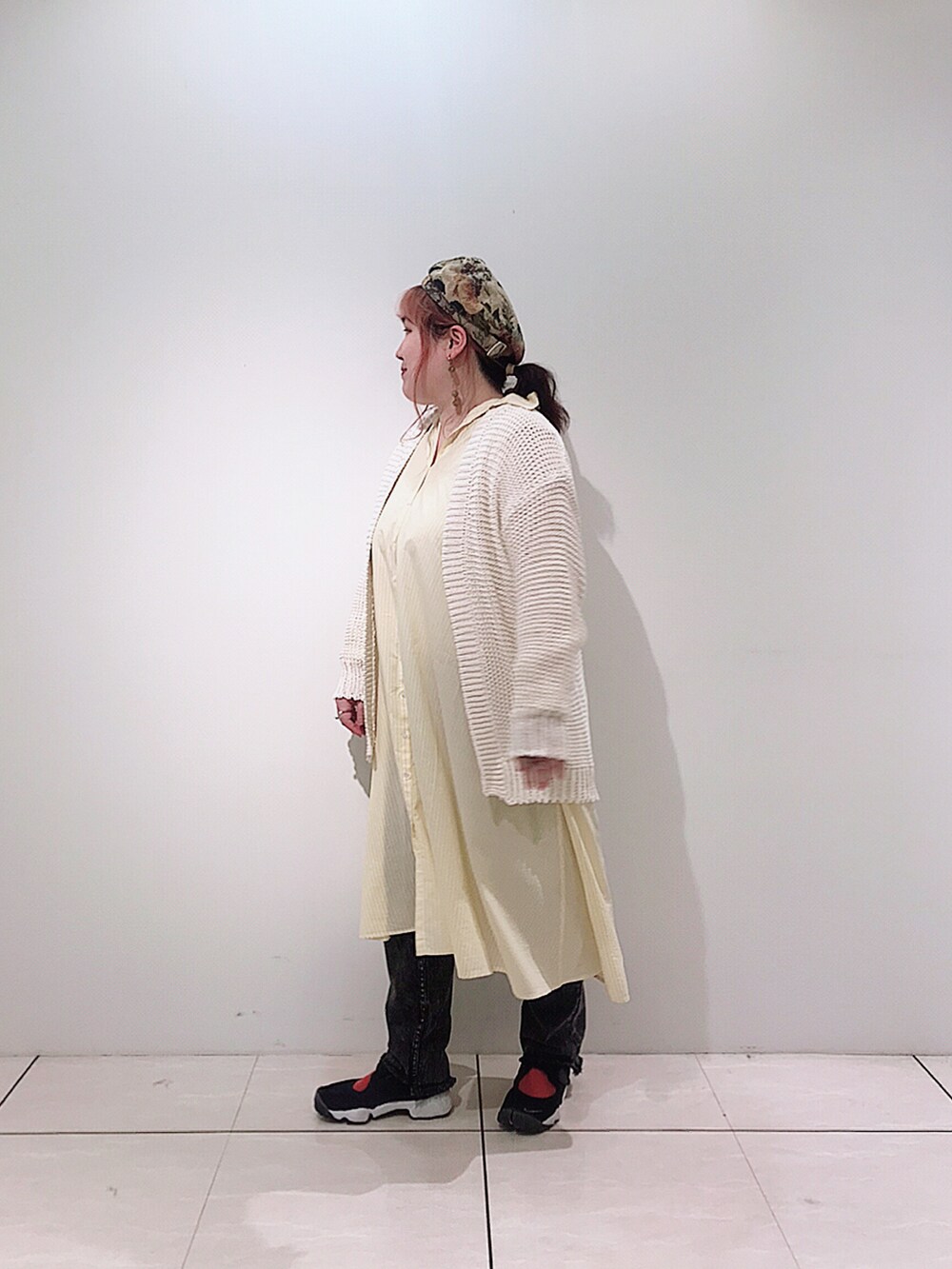 イエロー系のシャツワンピース、ホワイト系のカーディガン/ボレロ、グレー系のデニムパンツを着用したレディースの春コーディネートの4枚目の写真