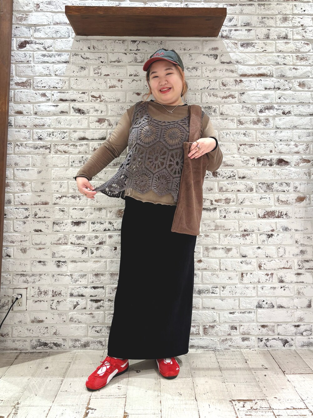 レッド系のスニーカー、グレー系のベスト、ブラック系のスカートを着用したレディースの秋コーディネートの2枚目の写真