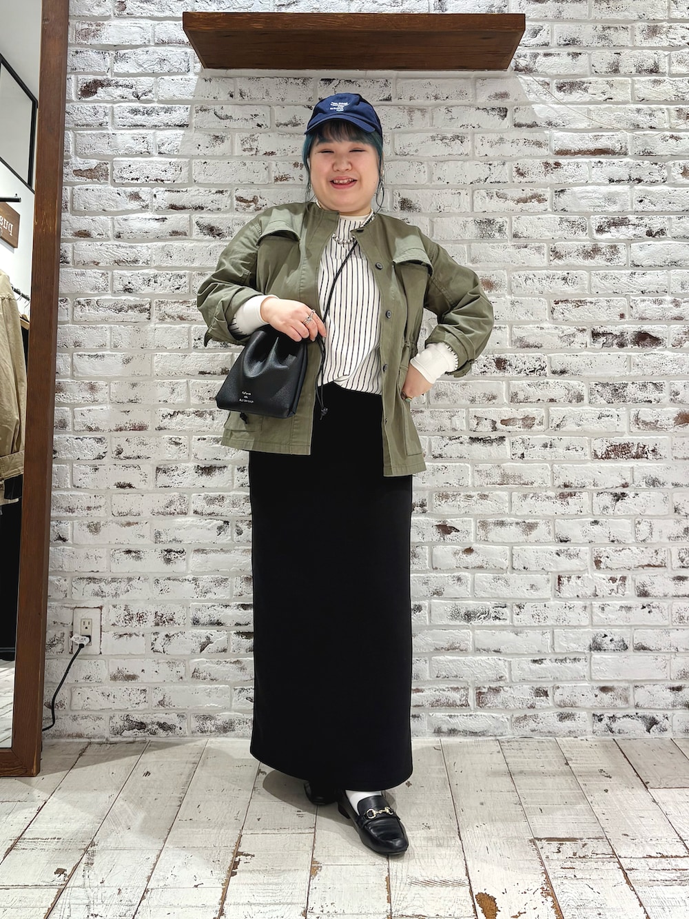 グリーン系のミリタリージャケット、その他のTシャツ/カットソー、ブラック系のスカートを着用したレディースの春コーディネートの2枚目の写真