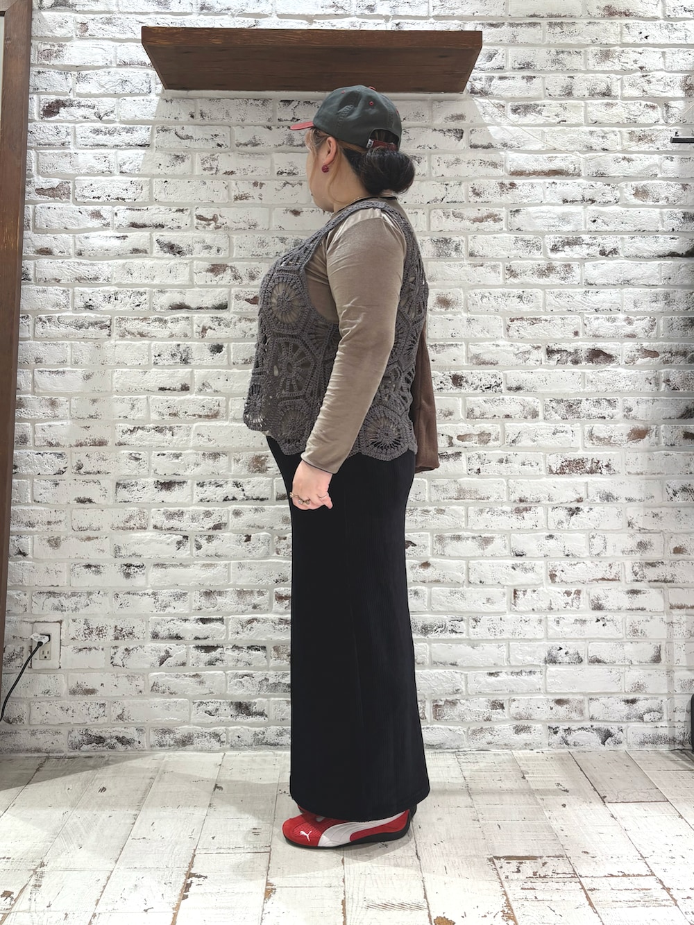 レッド系のスニーカー、グレー系のベスト、ブラック系のスカートを着用したレディースの秋コーディネートの3枚目の写真