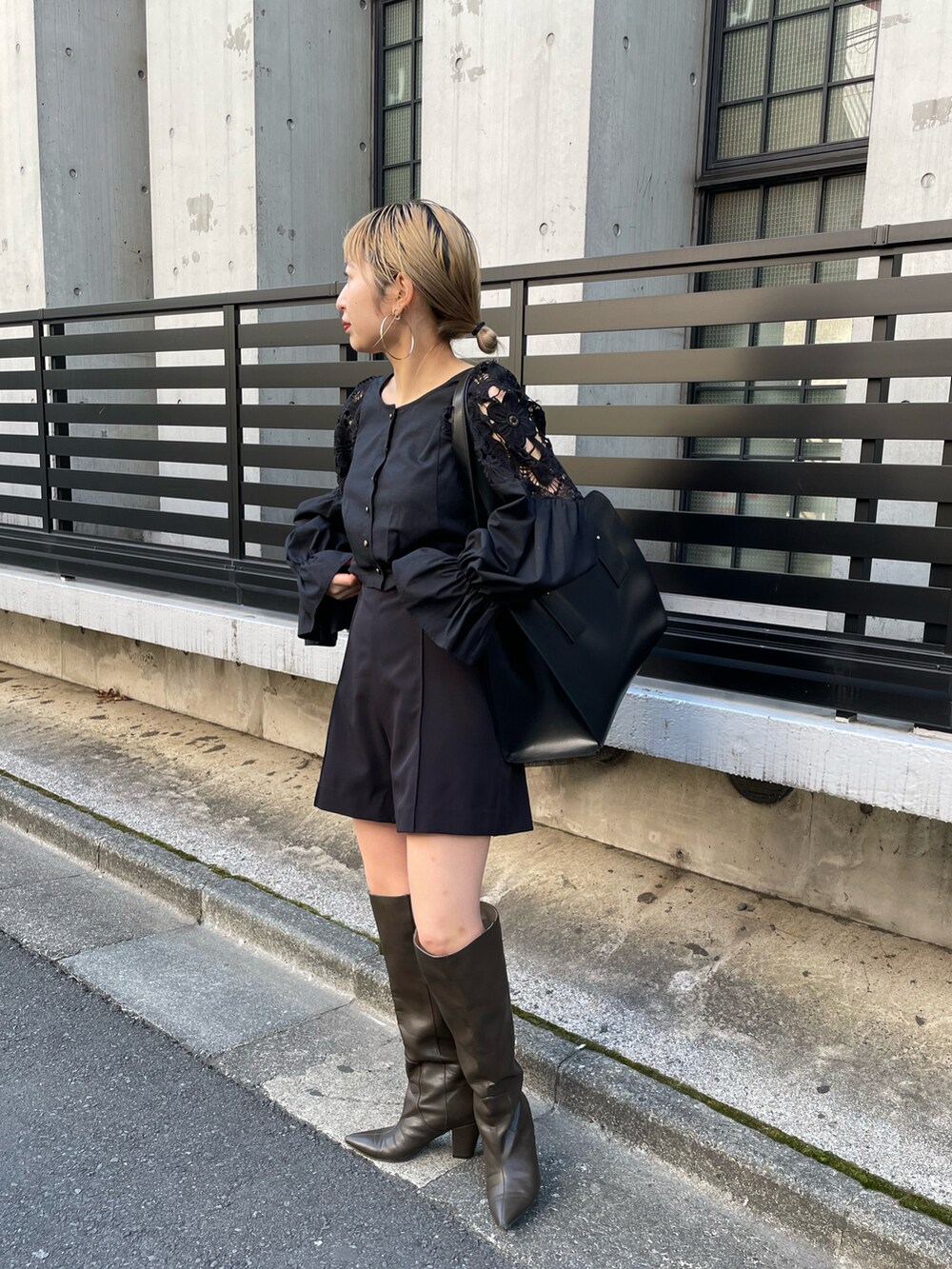 ブラウン系のトートバッグ、ブラック系のベスト、ブラック系のスラックスを着用したレディースの春コーディネートの2枚目の写真