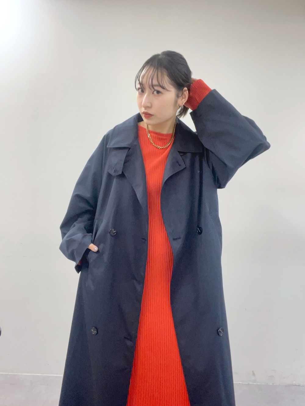 ブルー系のトレンチコート、オレンジ系のワンピースを着用したレディースの冬コーディネートの2枚目の写真