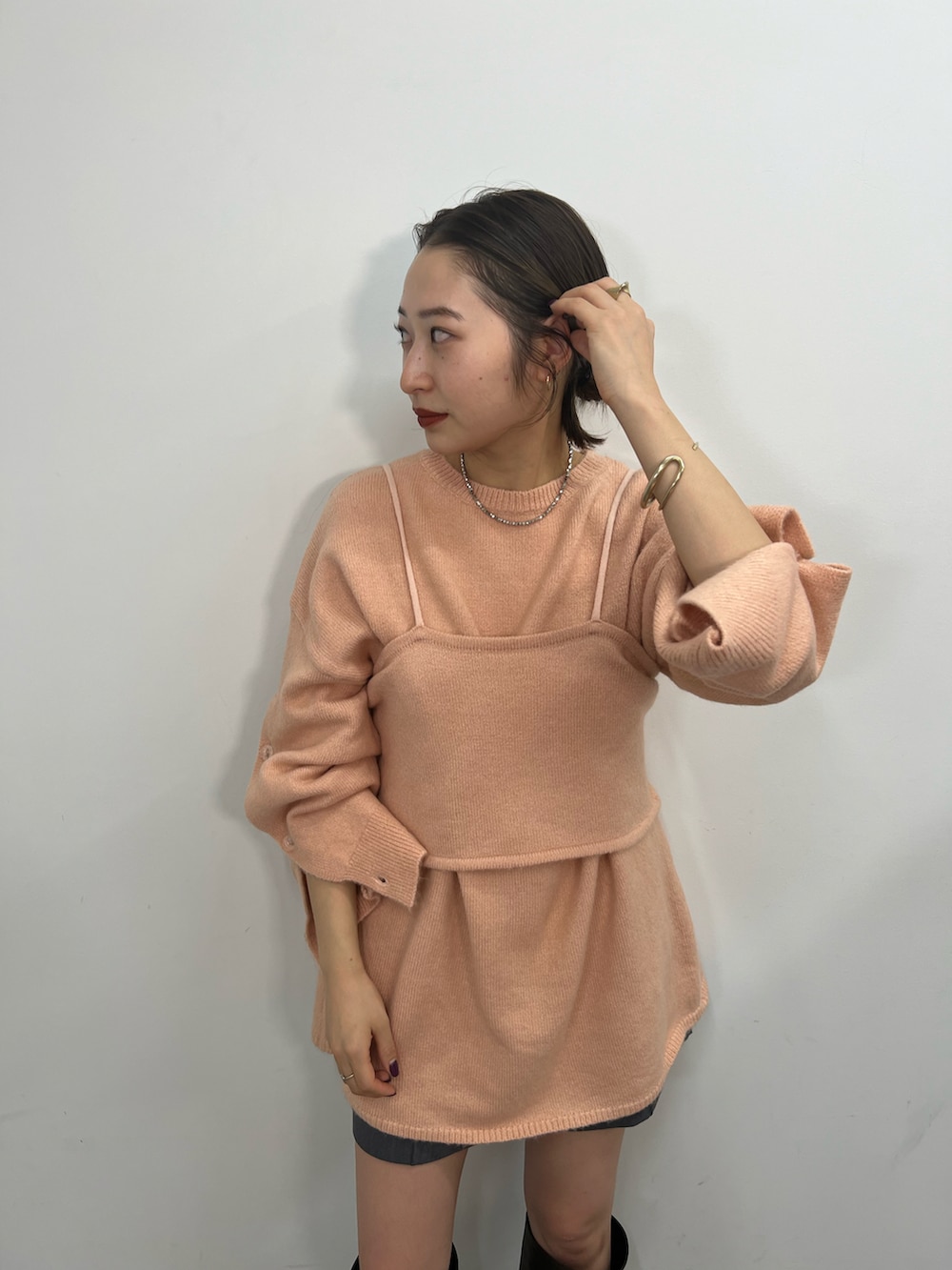 ピンク系のニット/セーター、ブラック系のブーツを着用したレディースの秋コーディネートの2枚目の写真