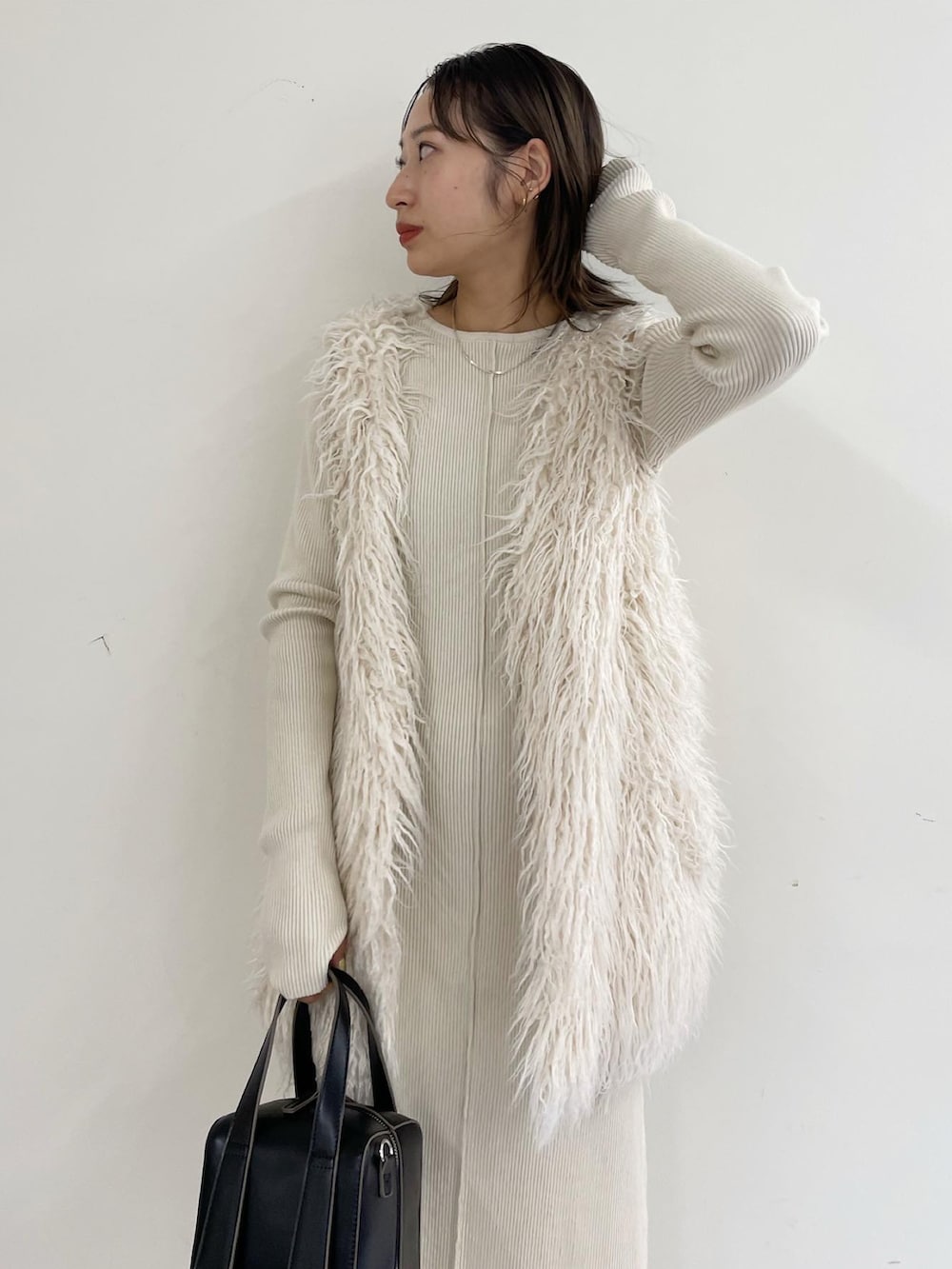 ホワイト系のベスト、グリーン系のボストンバッグ、ホワイト系のワンピースを着用したレディースの秋コーディネートの2枚目の写真