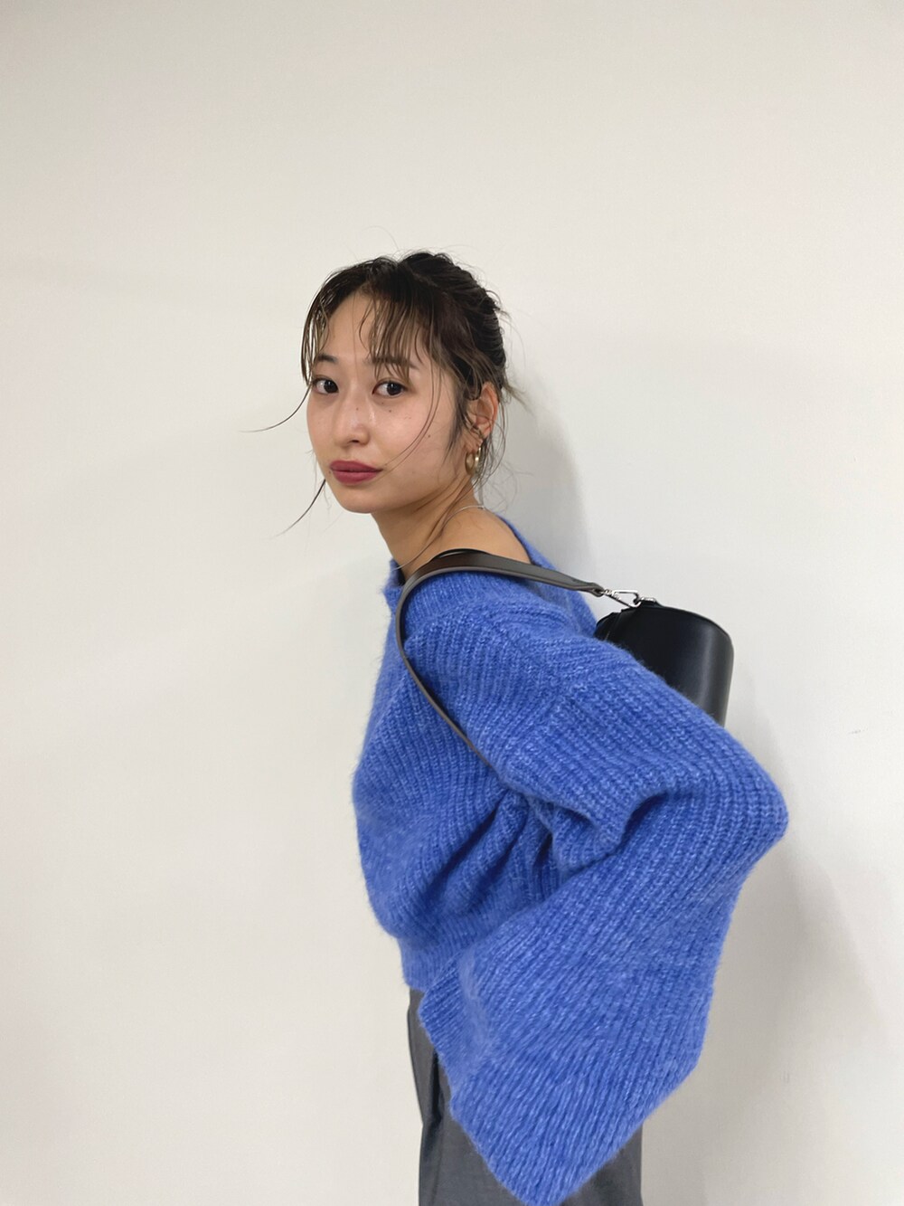 ブルー系のニット/セーター、グレー系のスラックス、ブラック系のスリッポンを着用したレディースの秋コーディネートの2枚目の写真