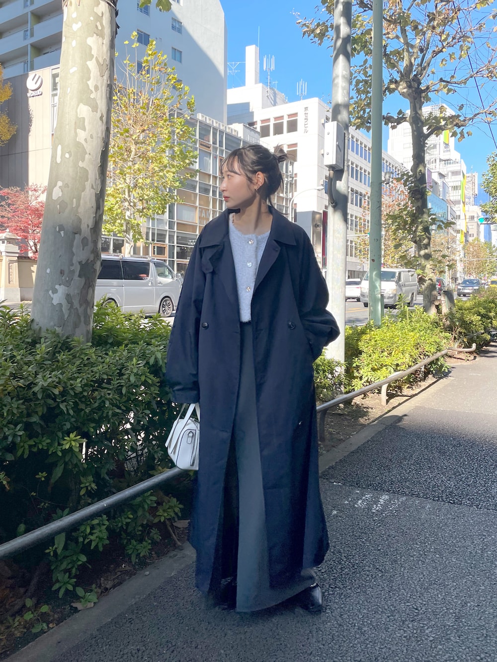 ホワイト系のショルダーバッグ、ブルー系のトレンチコート、ホワイト系のカーディガン/ボレロを着用したレディースの冬コーディネートの2枚目の写真