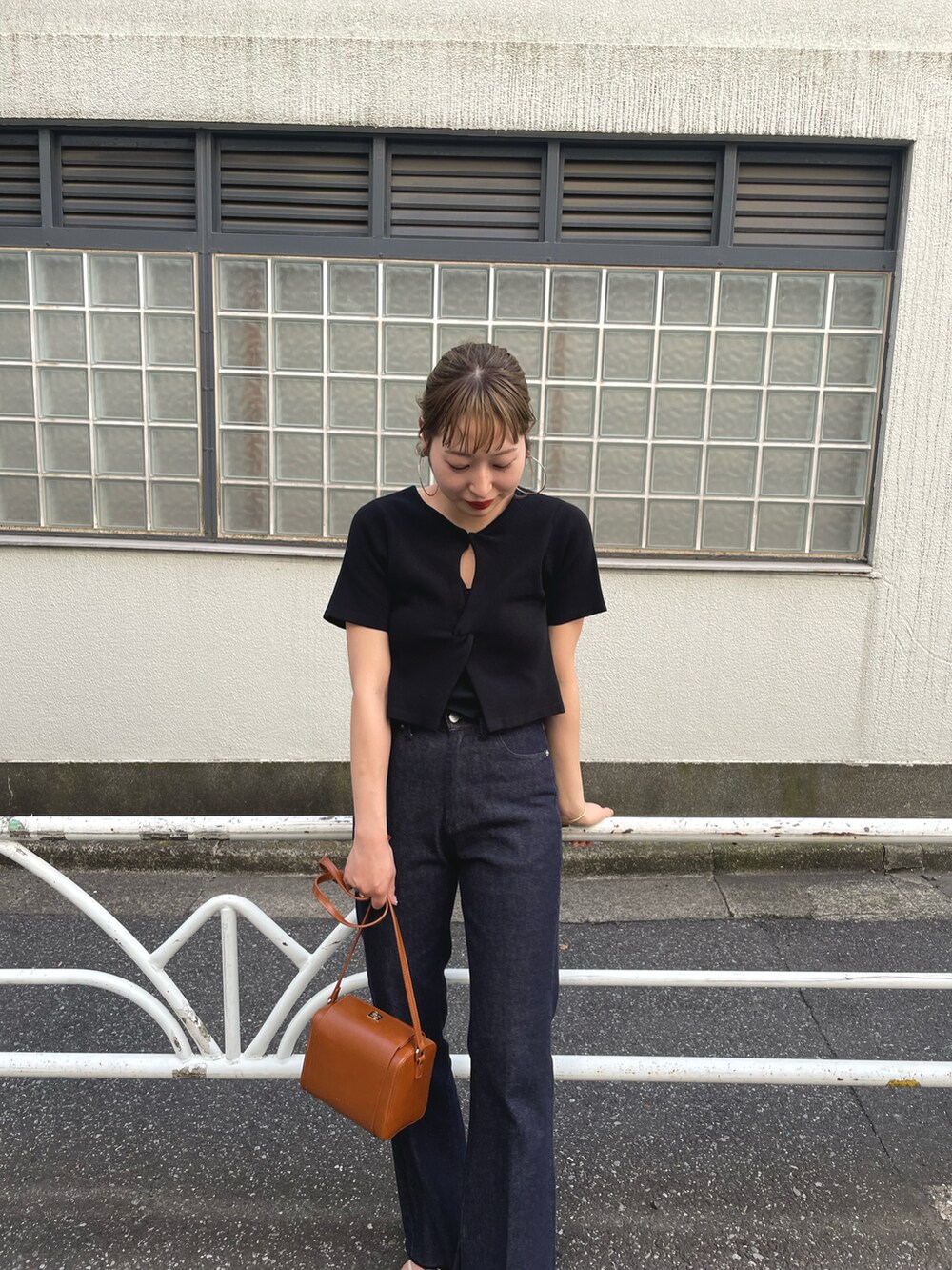 ブラック系のデニムパンツ、ブラック系のニット/セーター、ブラウン系のショルダーバッグを着用したレディースの春コーディネートの2枚目の写真