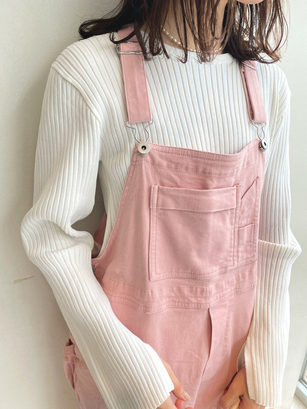 ホワイト系のニット/セーター、ピンク系のサロペット/オーバーオール、ホワイト系のショルダーバッグを着用したレディースの春コーディネートの3枚目の写真