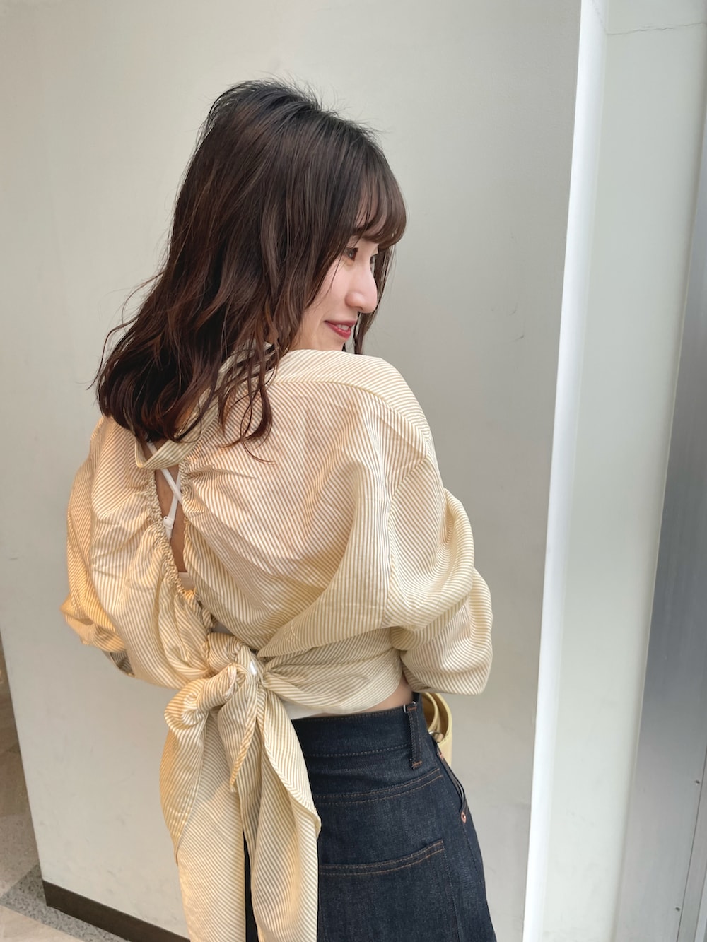 イエロー系のシャツ/ブラウス、ブルー系のデニムパンツ、シルバー系のサンダルを着用したレディースの春コーディネートの2枚目の写真