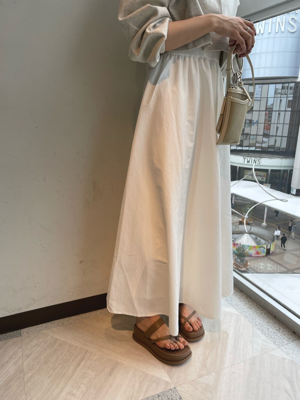 ホワイト系のワンピース、ベージュ系のショルダーバッグ、ブラウン系のサンダルを着用したレディースの春コーディネートの3枚目の写真