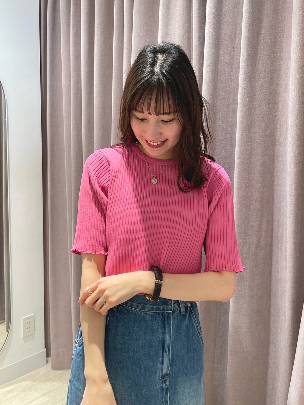 ピンク系のニット/セーター、ブルー系のデニムスカート、ブラック系のショルダーバッグを着用したレディースの春コーディネートの2枚目の写真