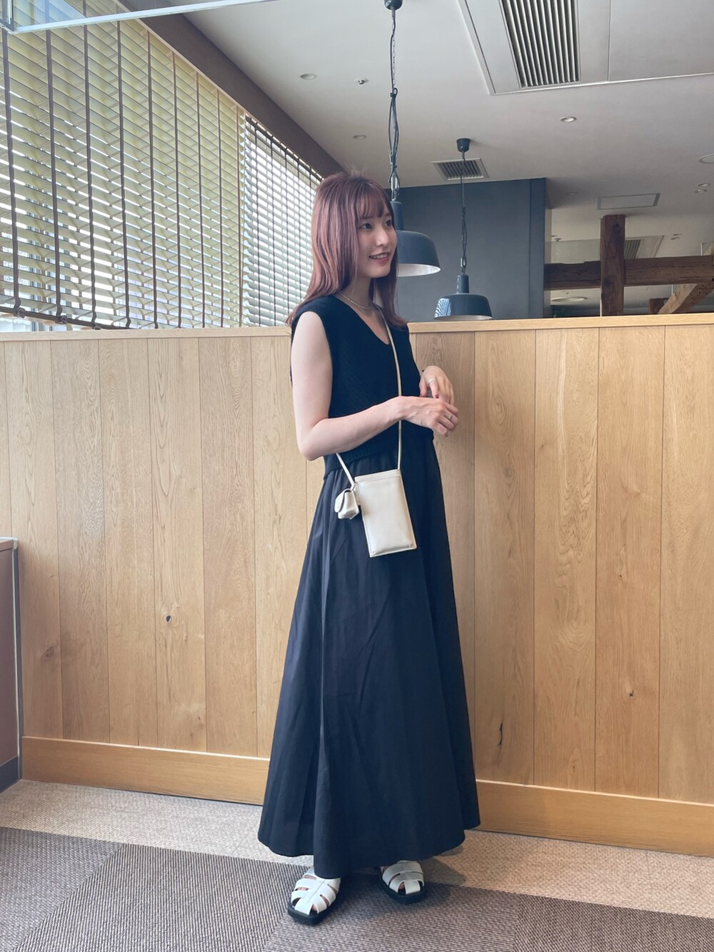 ブラック系のワンピース、ホワイト系のショルダーバッグ、ホワイト系のスリッポンを着用したレディースの夏コーディネートの3枚目の写真