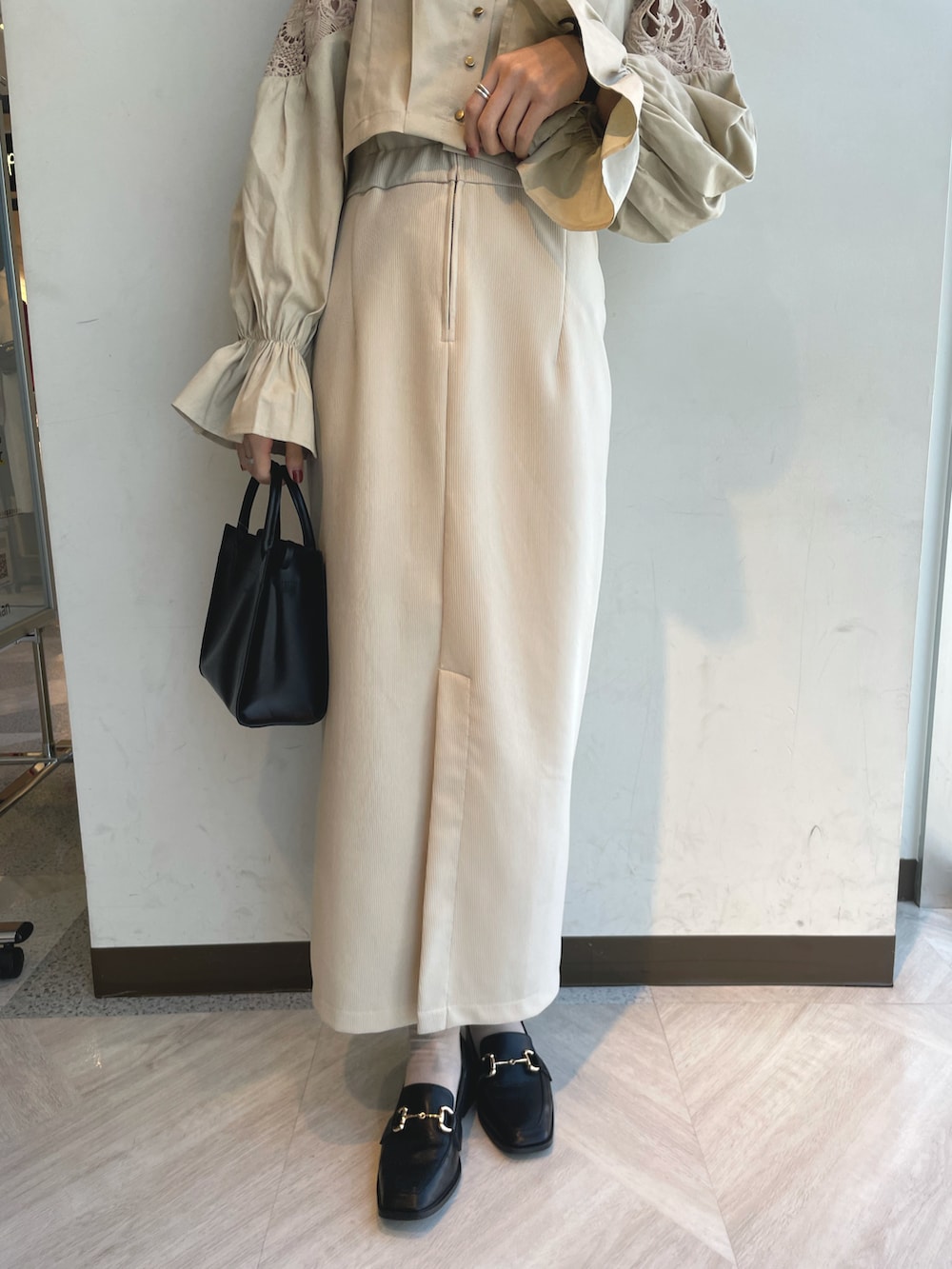 ベージュ系のシャツ/ブラウス、ベージュ系のスカート、ブラック系のトートバッグを着用したレディースの春コーディネートの3枚目の写真