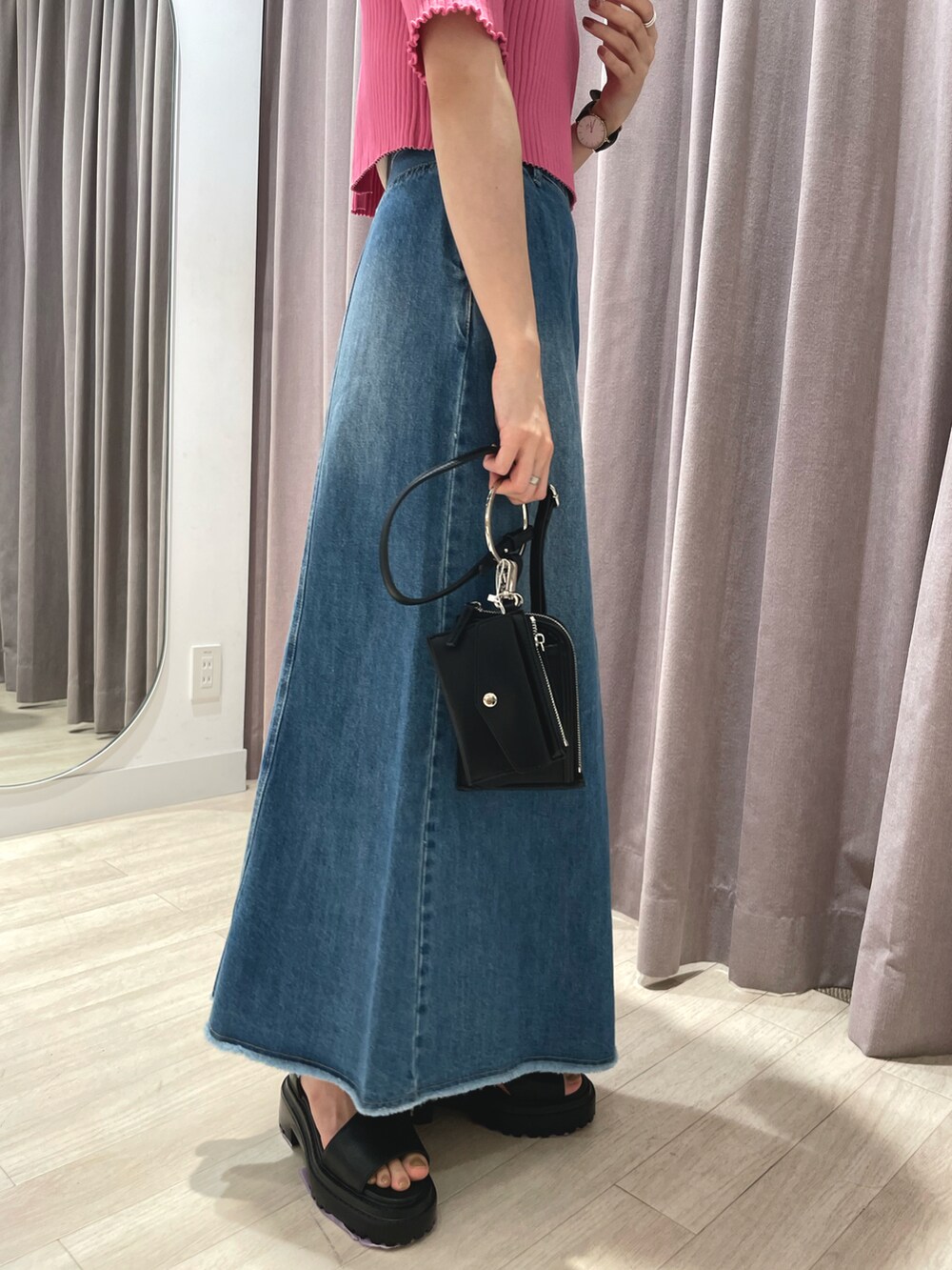 ピンク系のニット/セーター、ブルー系のデニムスカート、ブラック系のショルダーバッグを着用したレディースの春コーディネートの3枚目の写真