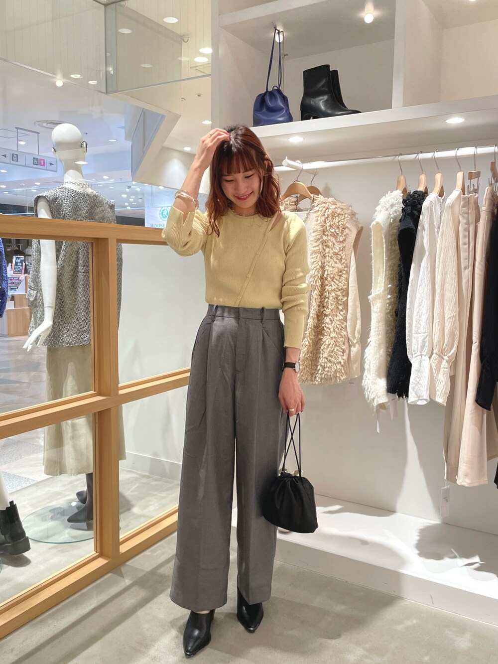 イエロー系のニット/セーター、グレー系のスラックス、ブラック系のスリッポンを着用したレディースの秋コーディネートの2枚目の写真