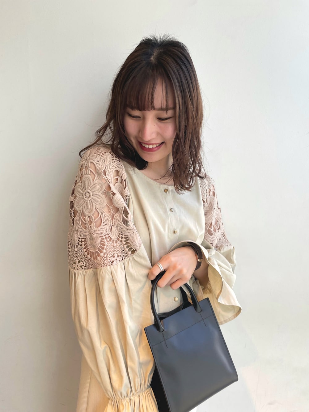 ベージュ系のシャツ/ブラウス、ベージュ系のスカート、ブラック系のトートバッグを着用したレディースの春コーディネートの2枚目の写真