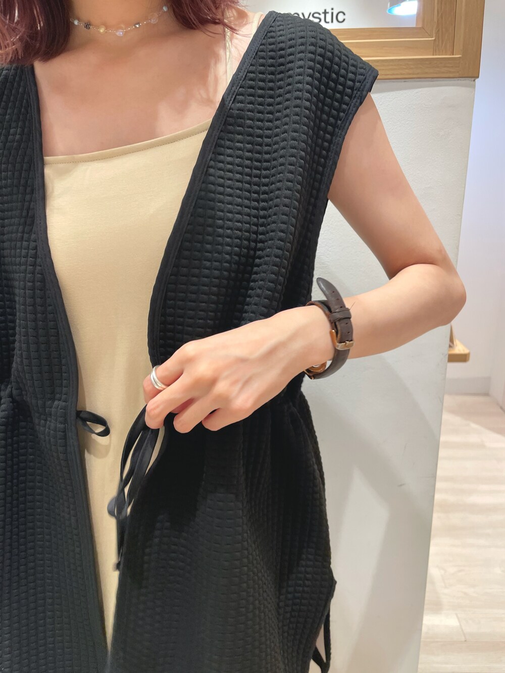 ブラック系のベスト、ベージュ系のワンピース、ブルー系のショルダーバッグを着用したレディースの夏コーディネートの2枚目の写真