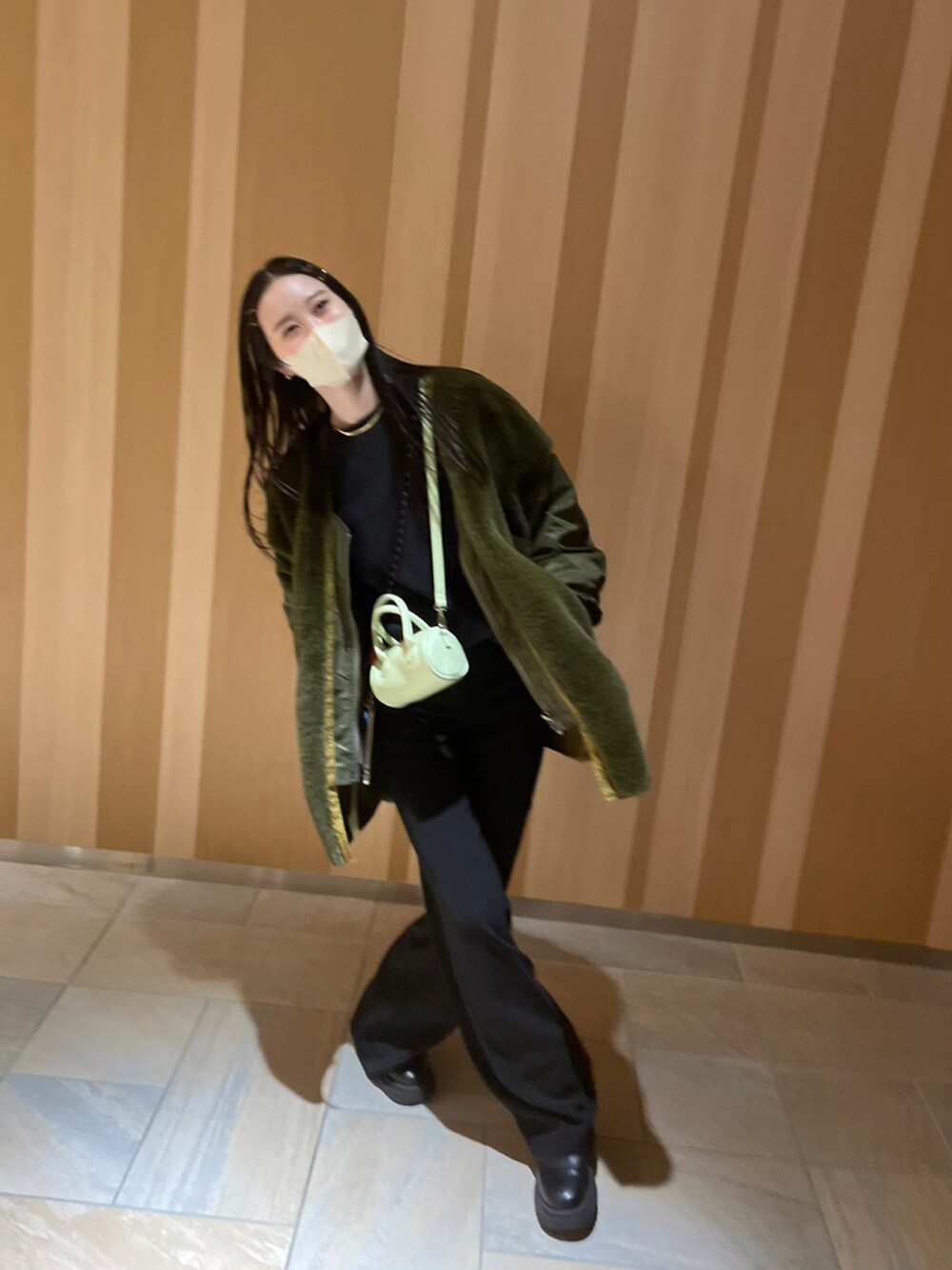 グリーン系のショルダーバッグ、ブラック系のブーツを着用したレディースの冬コーディネートの4枚目の写真