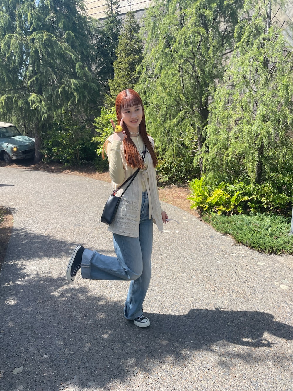 ブルー系のデニムパンツ、ベージュ系のベスト、ブラック系のスニーカーを着用したレディースの春コーディネートの3枚目の写真