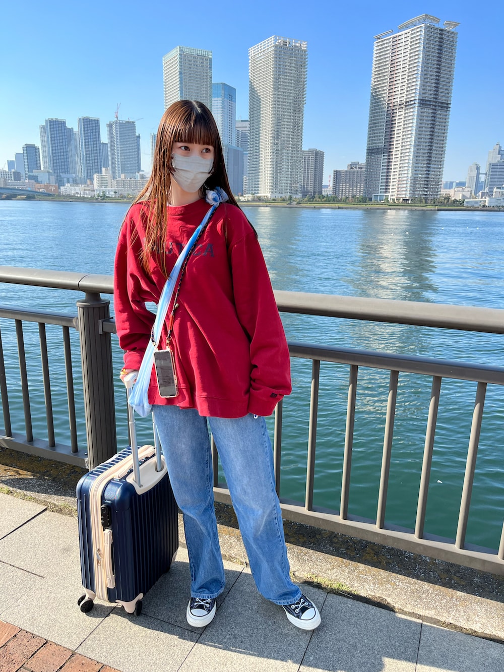 レッド系のスウェット、ブルー系のデニムパンツを着用したレディースの秋コーディネートの2枚目の写真